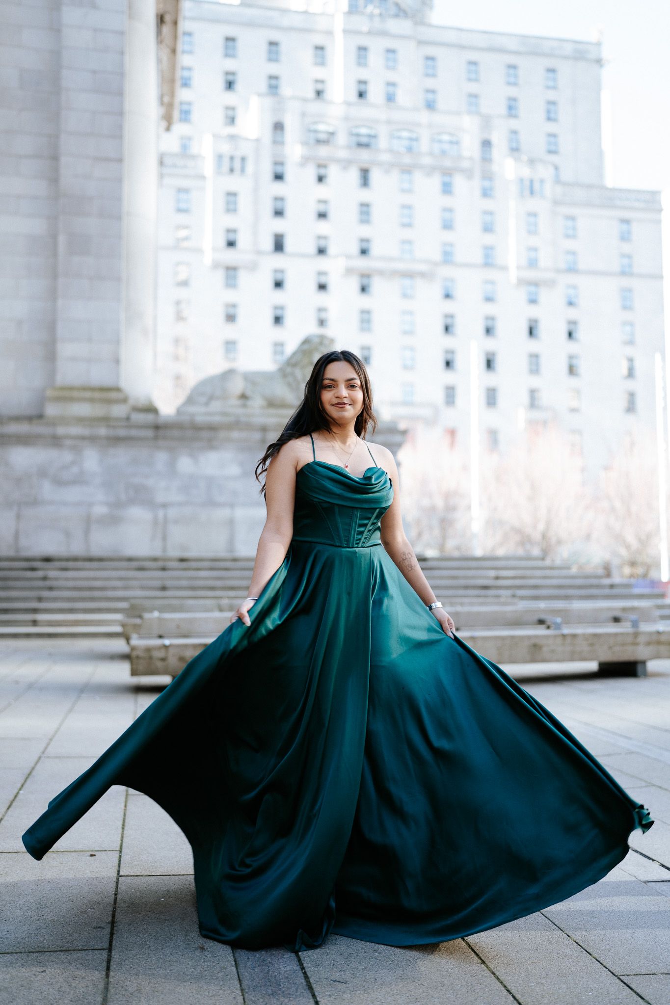 A sequence of photos showing a flowing emerald green gown twirling gracefully against an architectural backdrop.