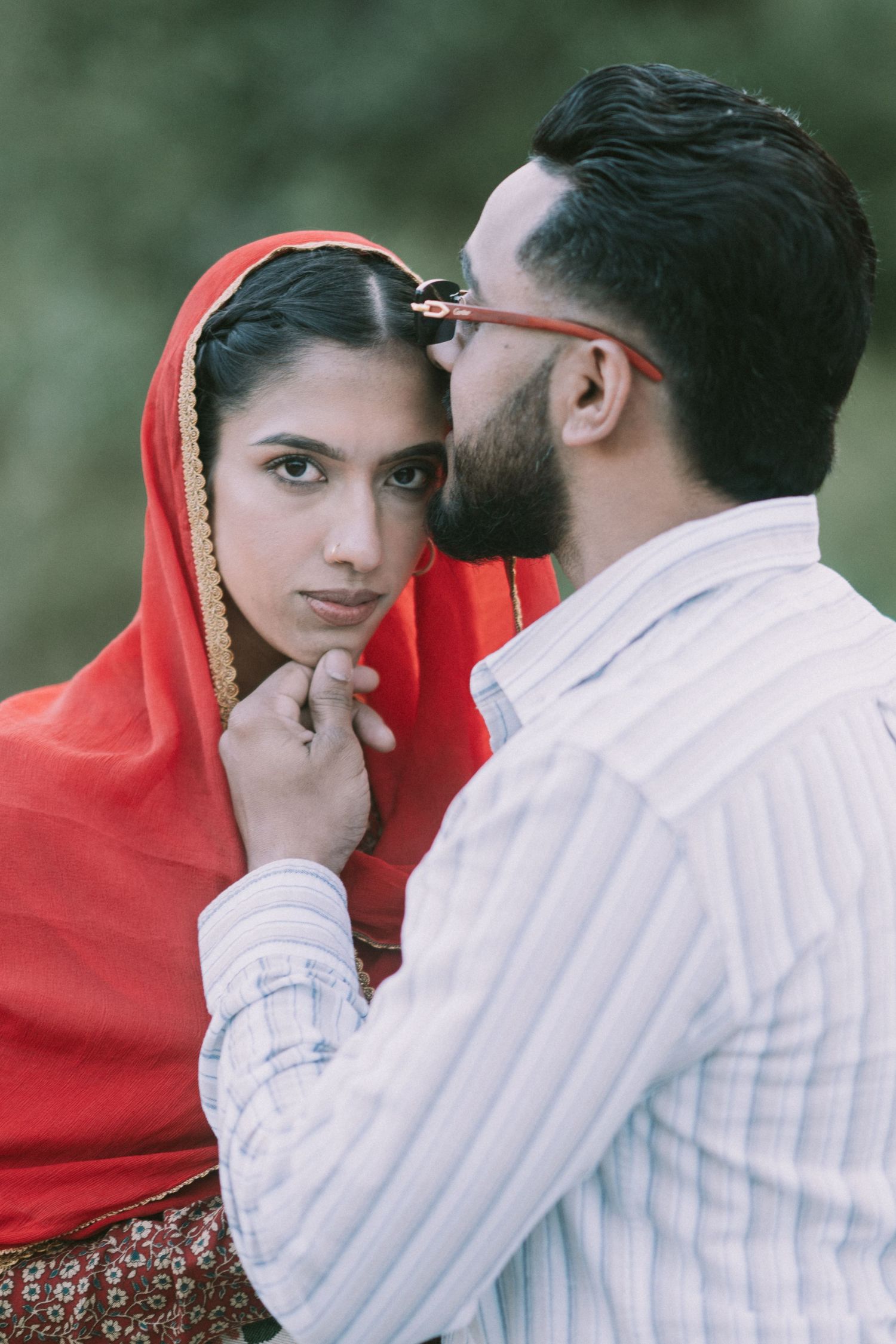 A romantic sequence showing a couple in traditional attire with a red dupatta sharing tender moments outdoors.