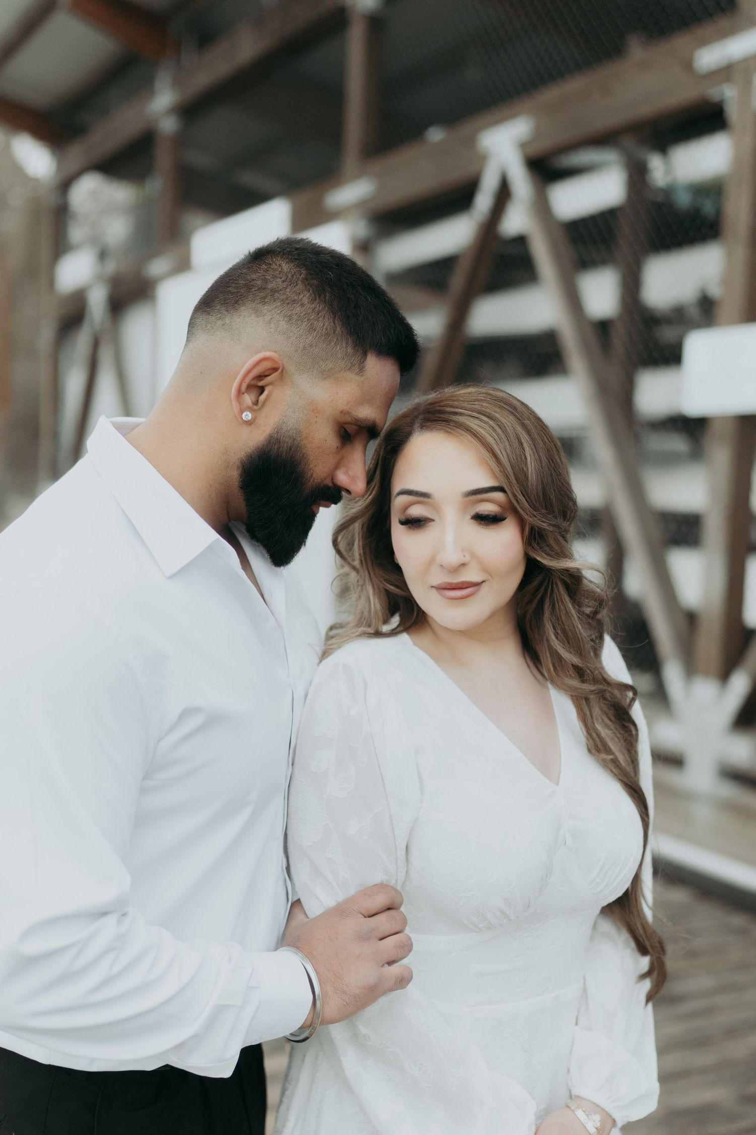 An intimate couples photoshoot with white and black attire against an industrial backdrop.