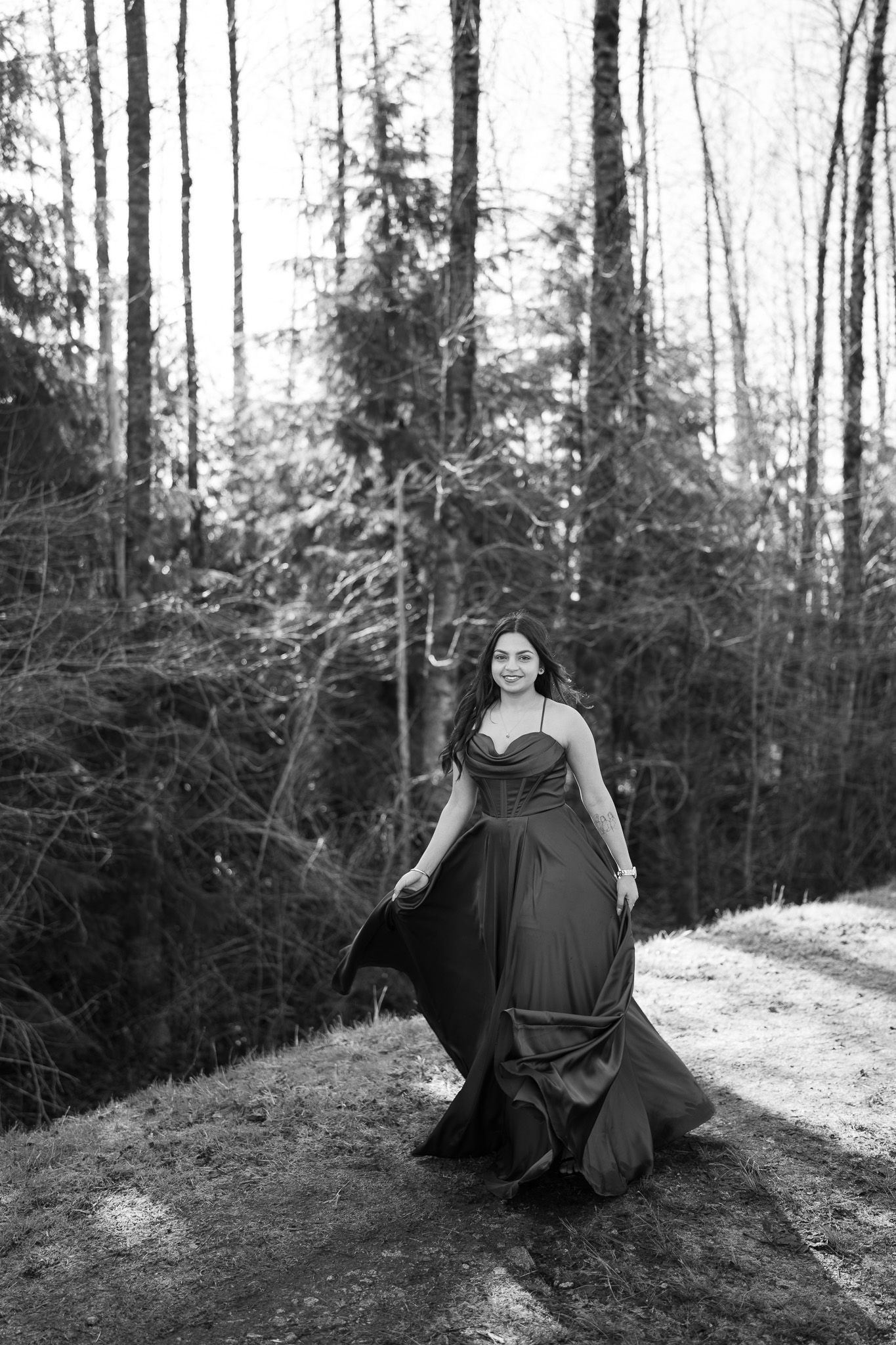 Black and white photos of someone in a flowing dress walking and posing dramatically in a wooded forest setting.