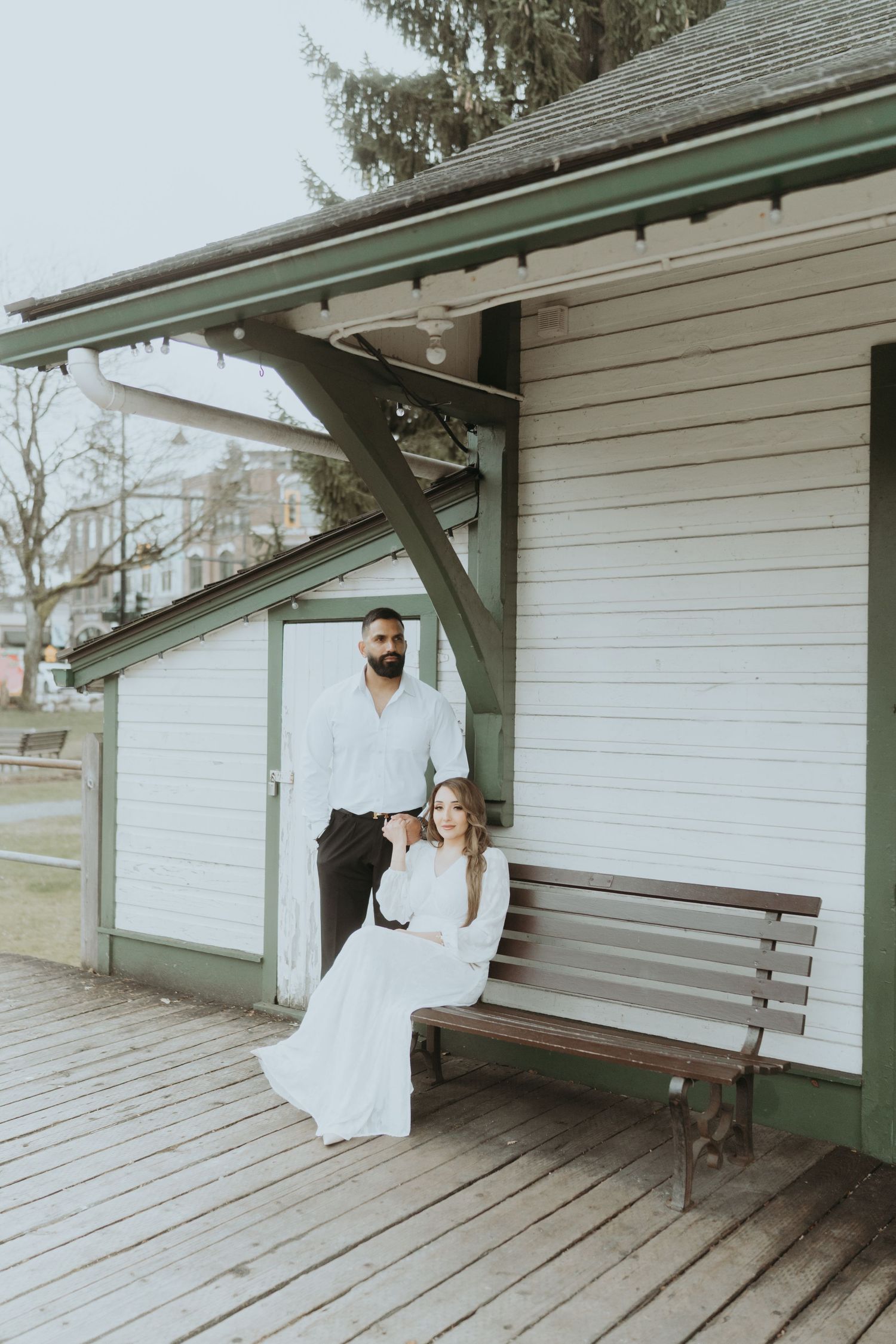 Artistic wedding photos captured at a rustic train station platform with wooden benches.