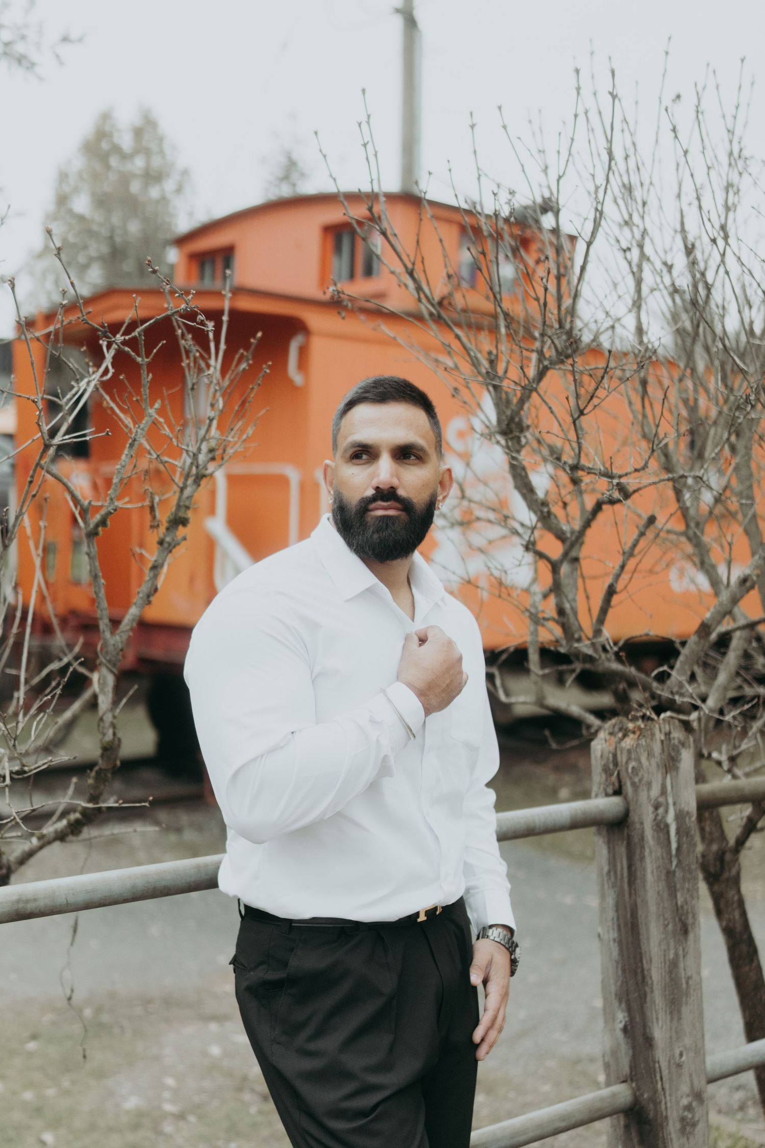 Fashion portrait near orange train car with dramatic poses against bare trees.