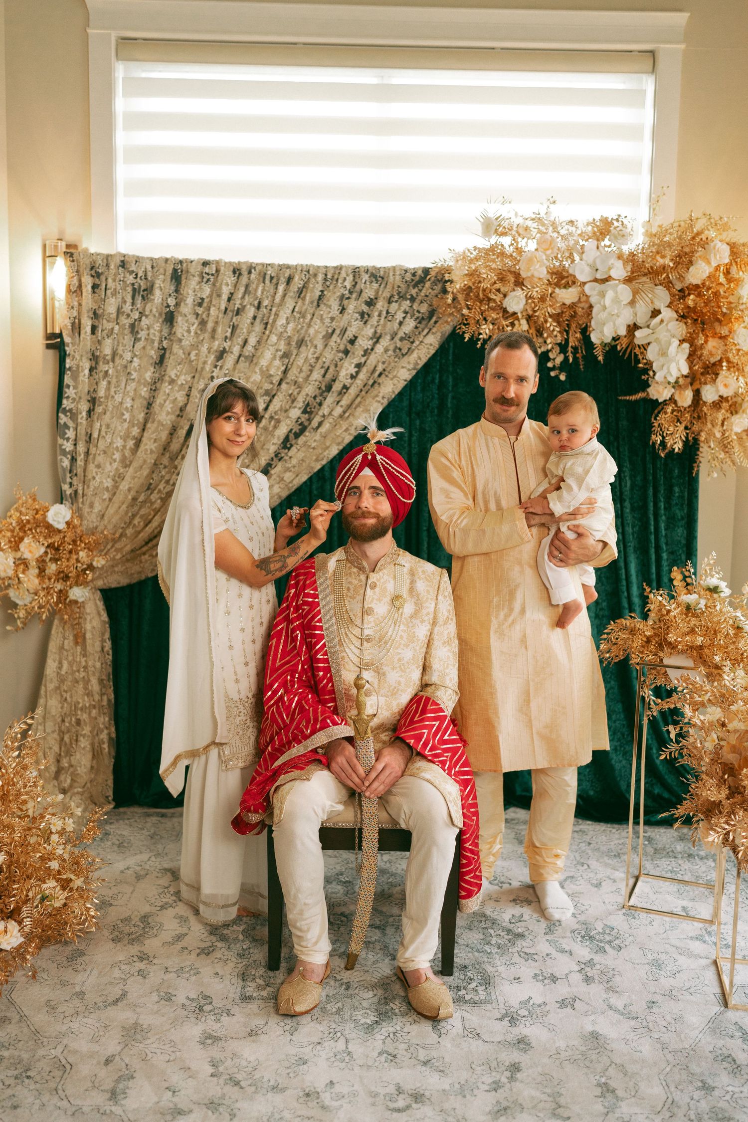 Family posing in traditional South Asian attire at an elegant wedding ceremony with gold floral decor.