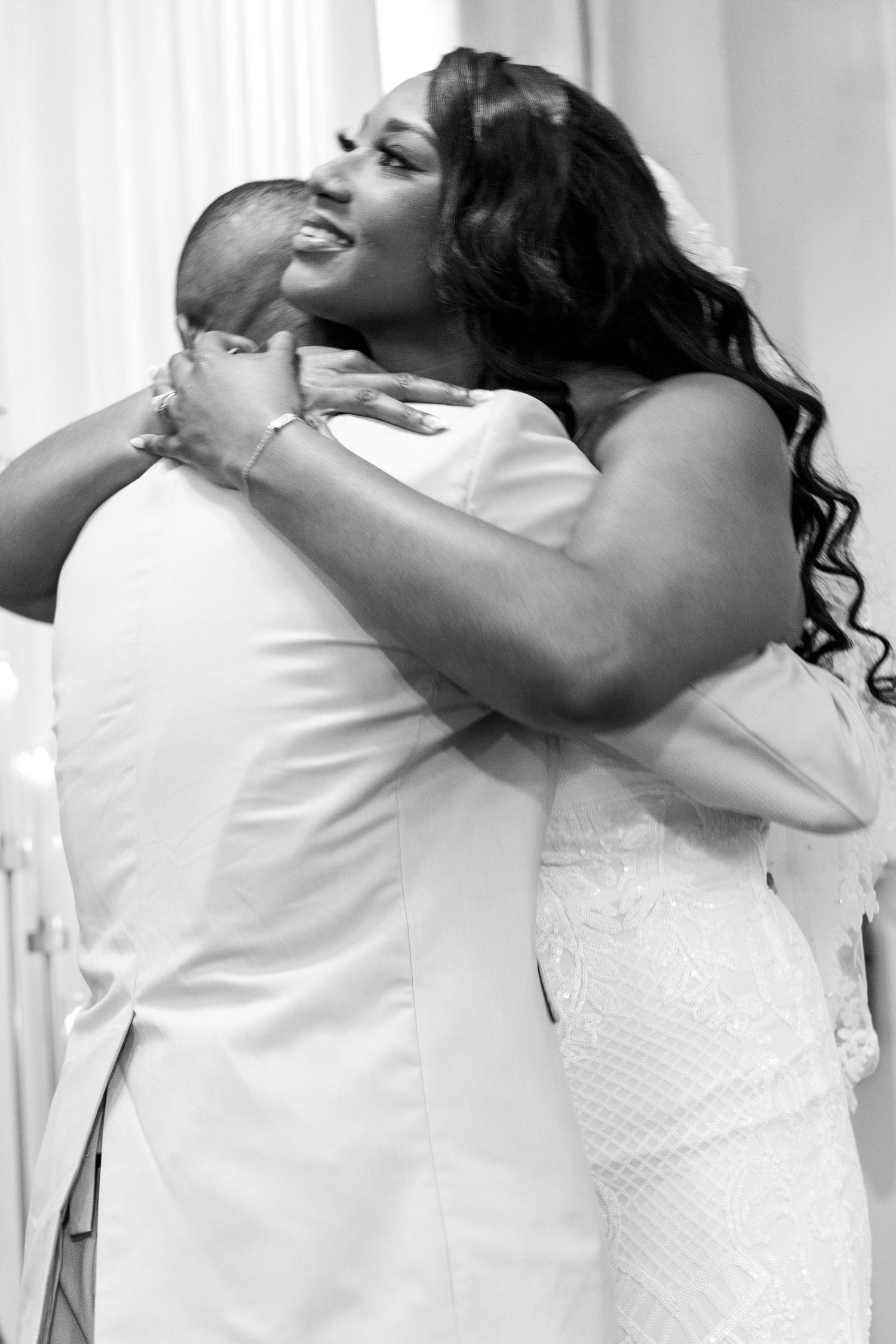 Black and white photo of bride and groom sharing emotional embrace at wedding ceremony.