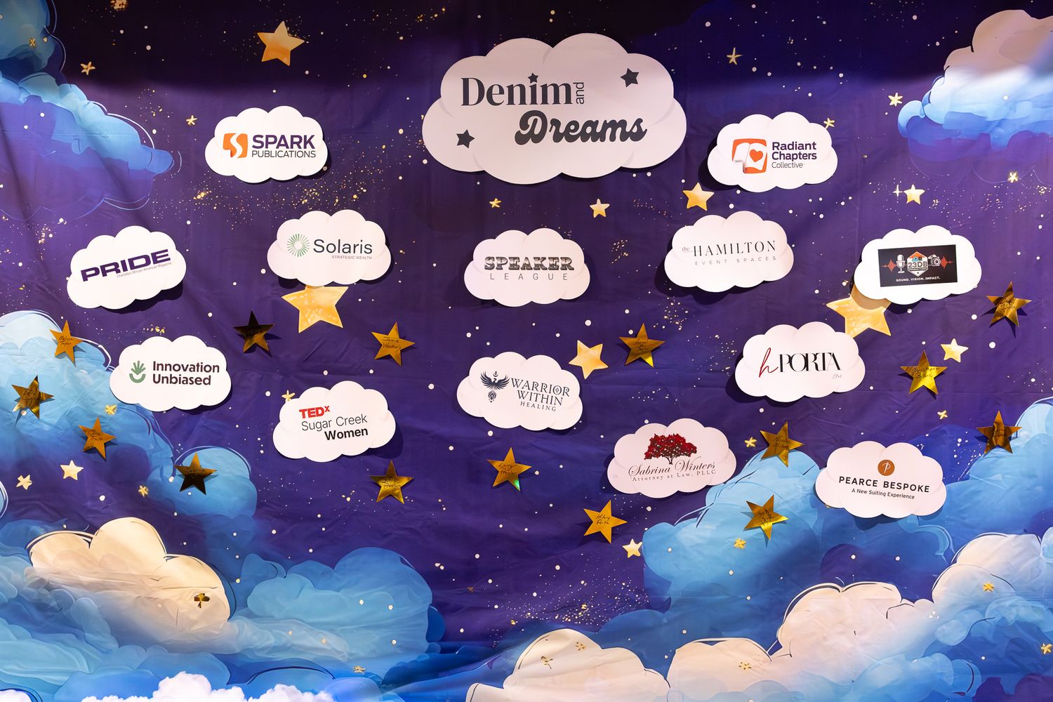 Denim Dreams event backdrop with sponsor logos on clouds against a starry night sky.
