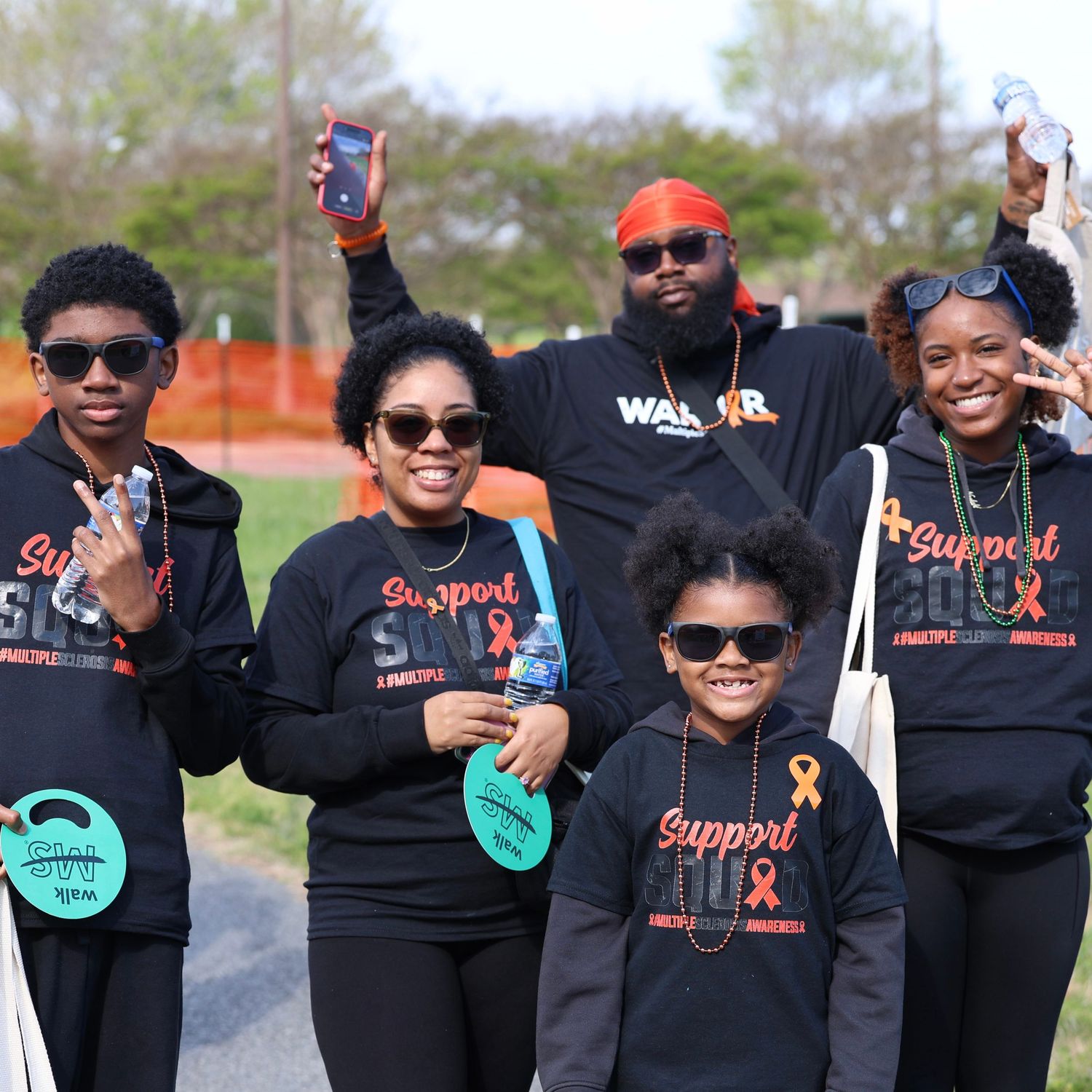 Group of people wearing black Support SHO awareness shirts posing together outdoors at a charity walk event. Multiple Sclerosis. Walk MS