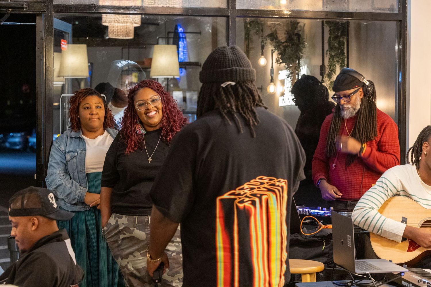 Group of musicians and performers socializing backstage at an intimate indoor music event.