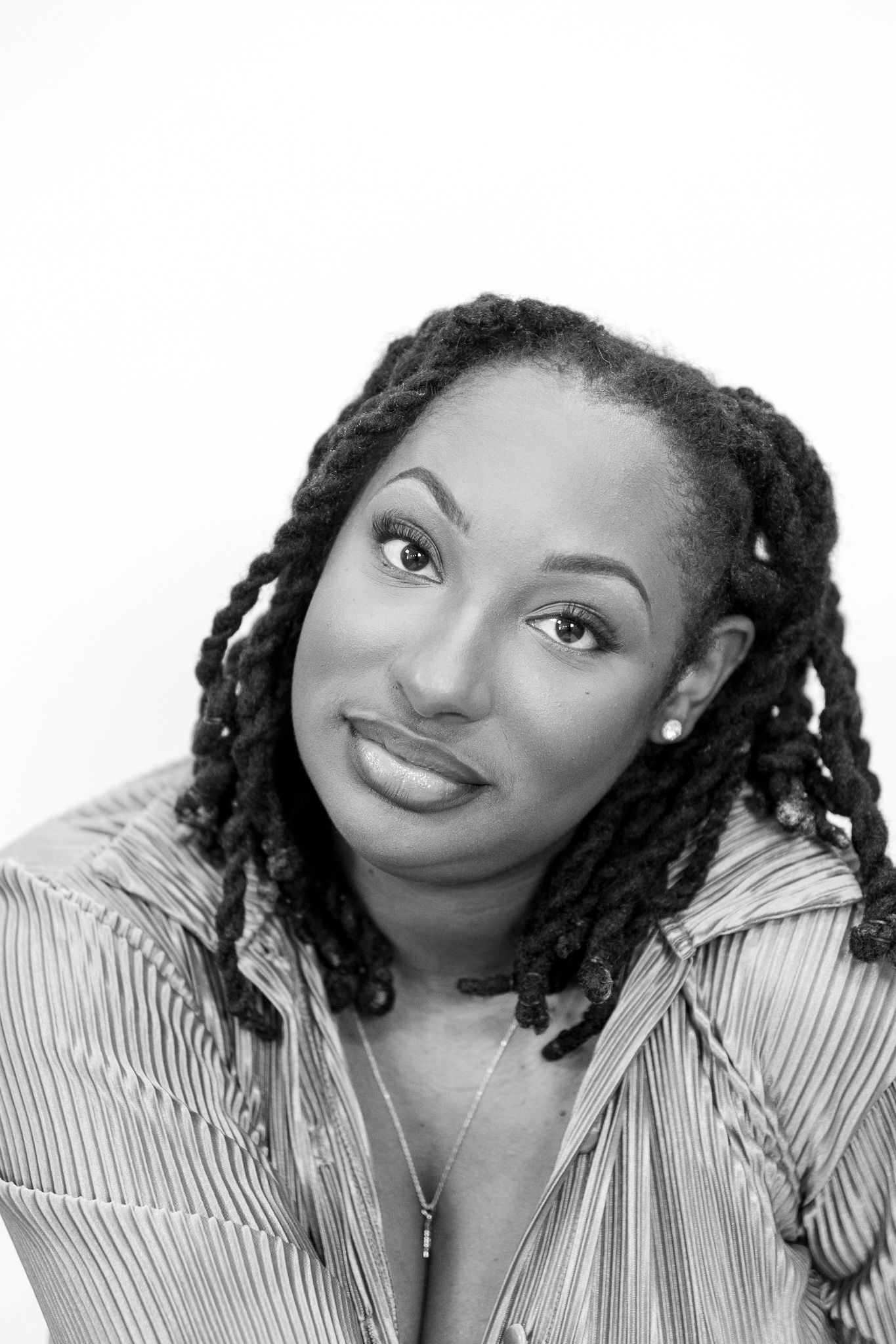Black and white portrait of a woman with locs hairstyle smiling against a white background.