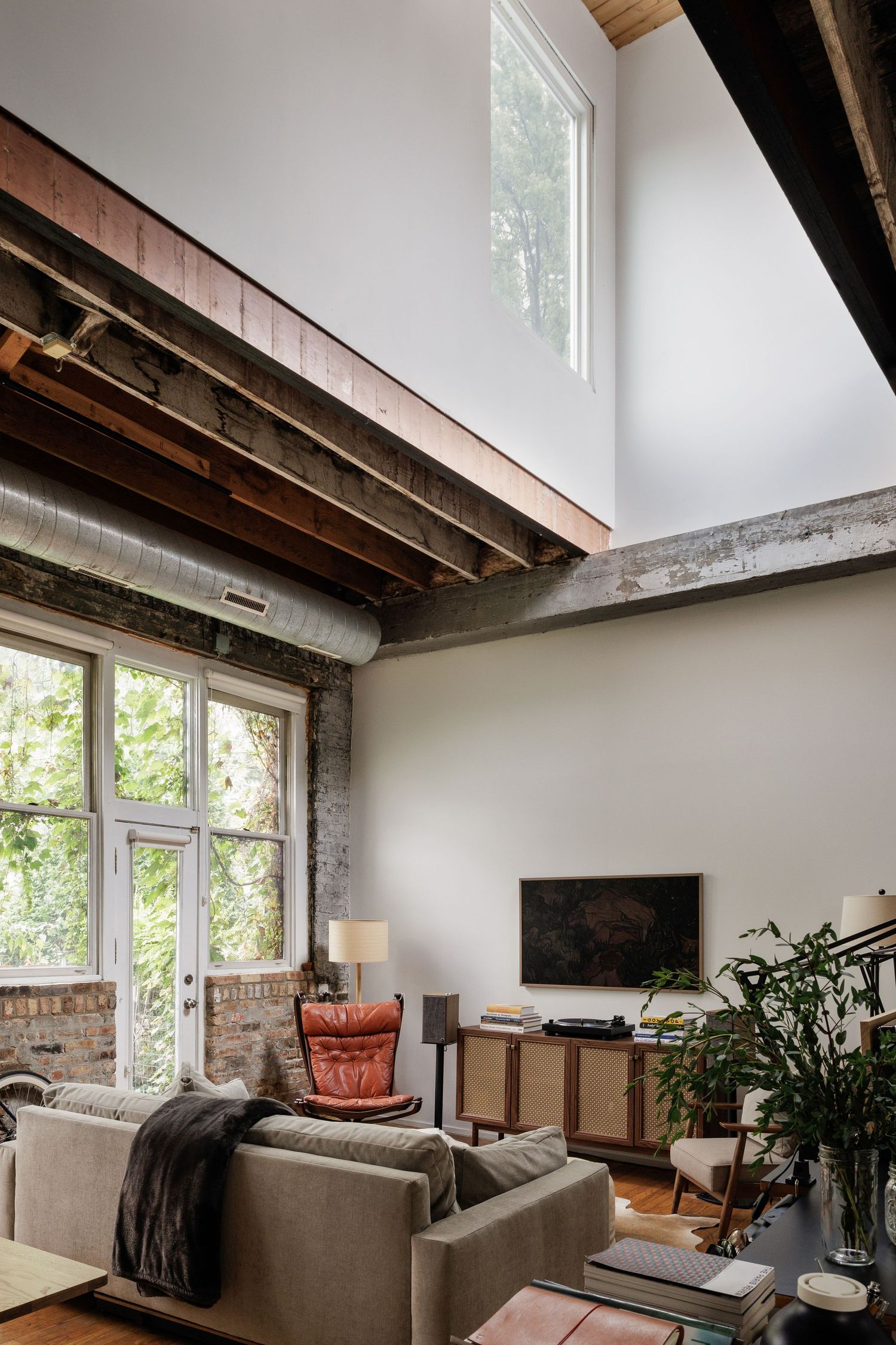 Modern loft interior with exposed wood beams, white walls, and large windows letting in natural light.