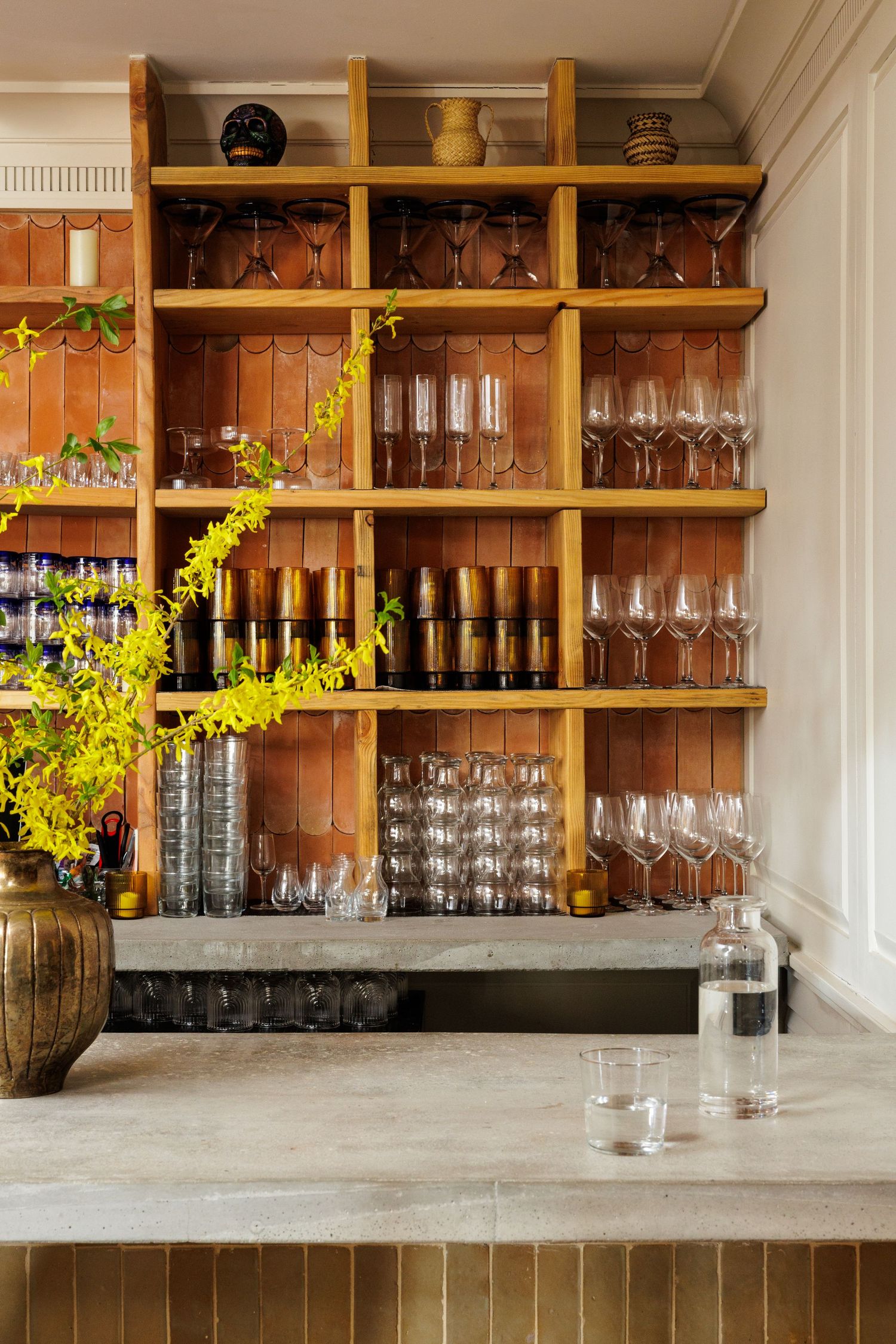 Bar shelving with organized glassware collection and concrete countertop.