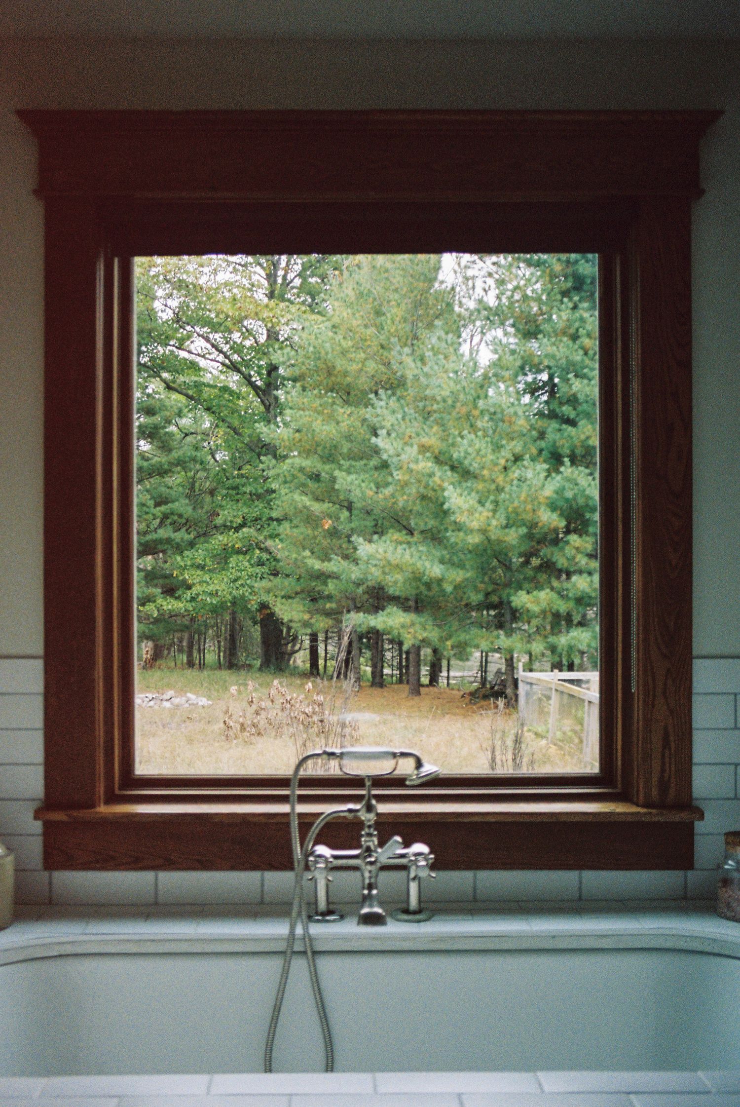 Modern bathroom with large window offering scenic forest views and contemporary fixtures.
