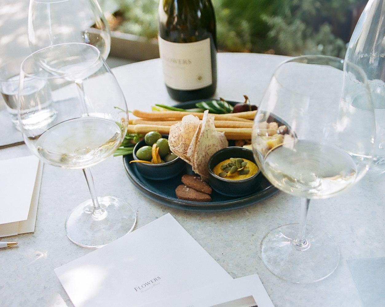 Elegant table setting with wine glasses and appetizers in natural lighting.