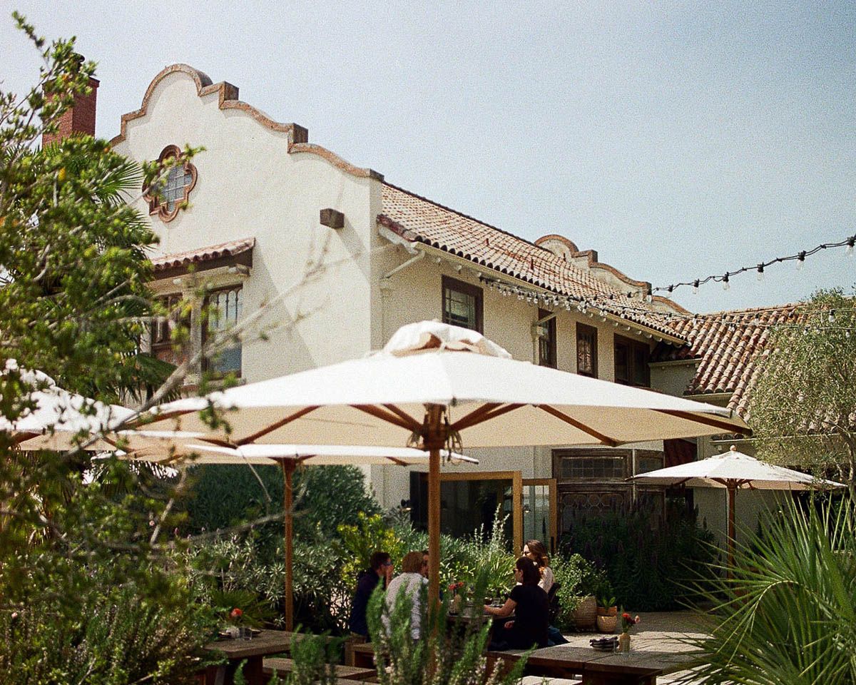 Mediterranean style courtyard with white stucco buildings and patio umbrellas.