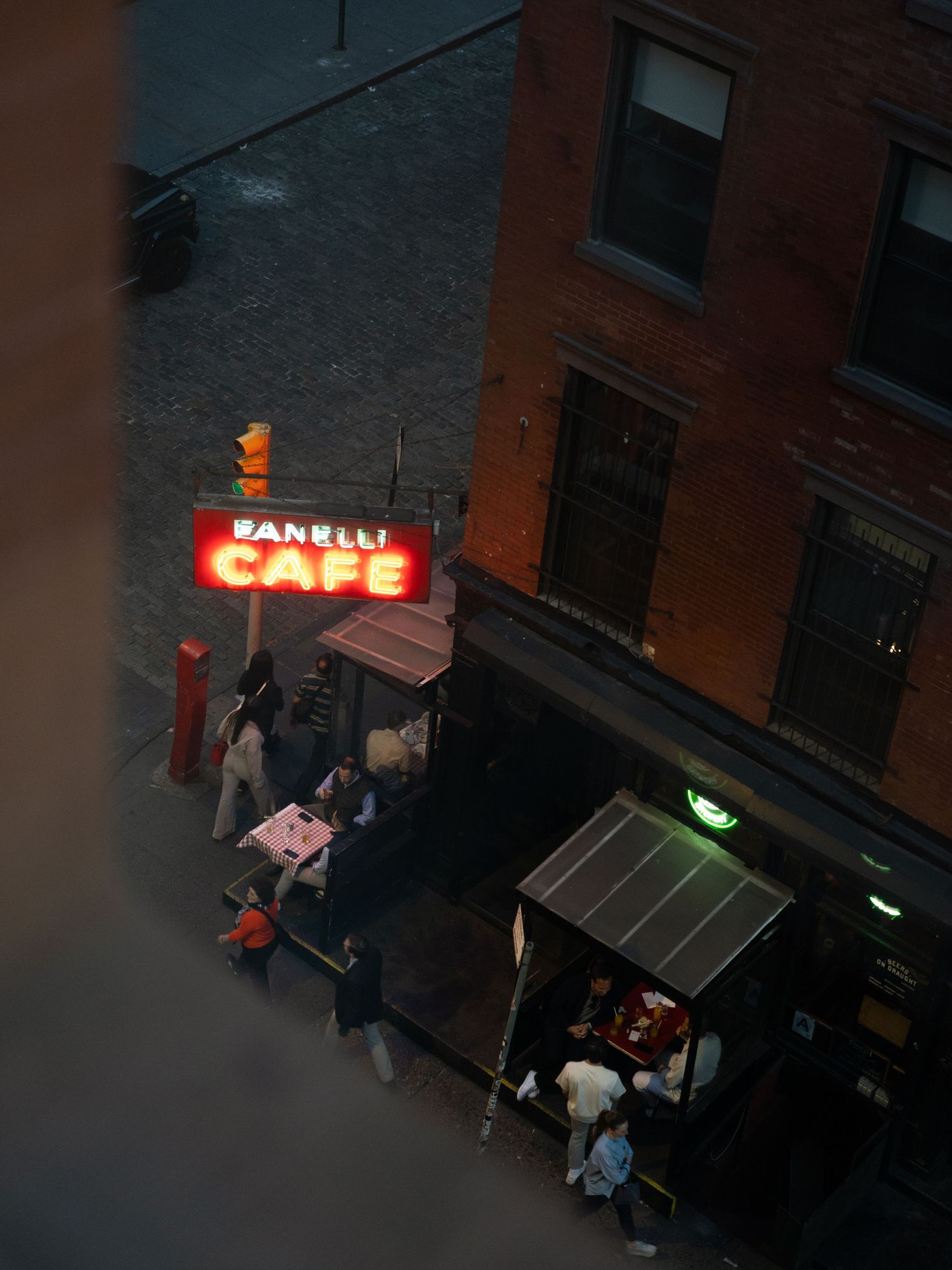 Night view of an illuminated cafe sign and street scene from above.