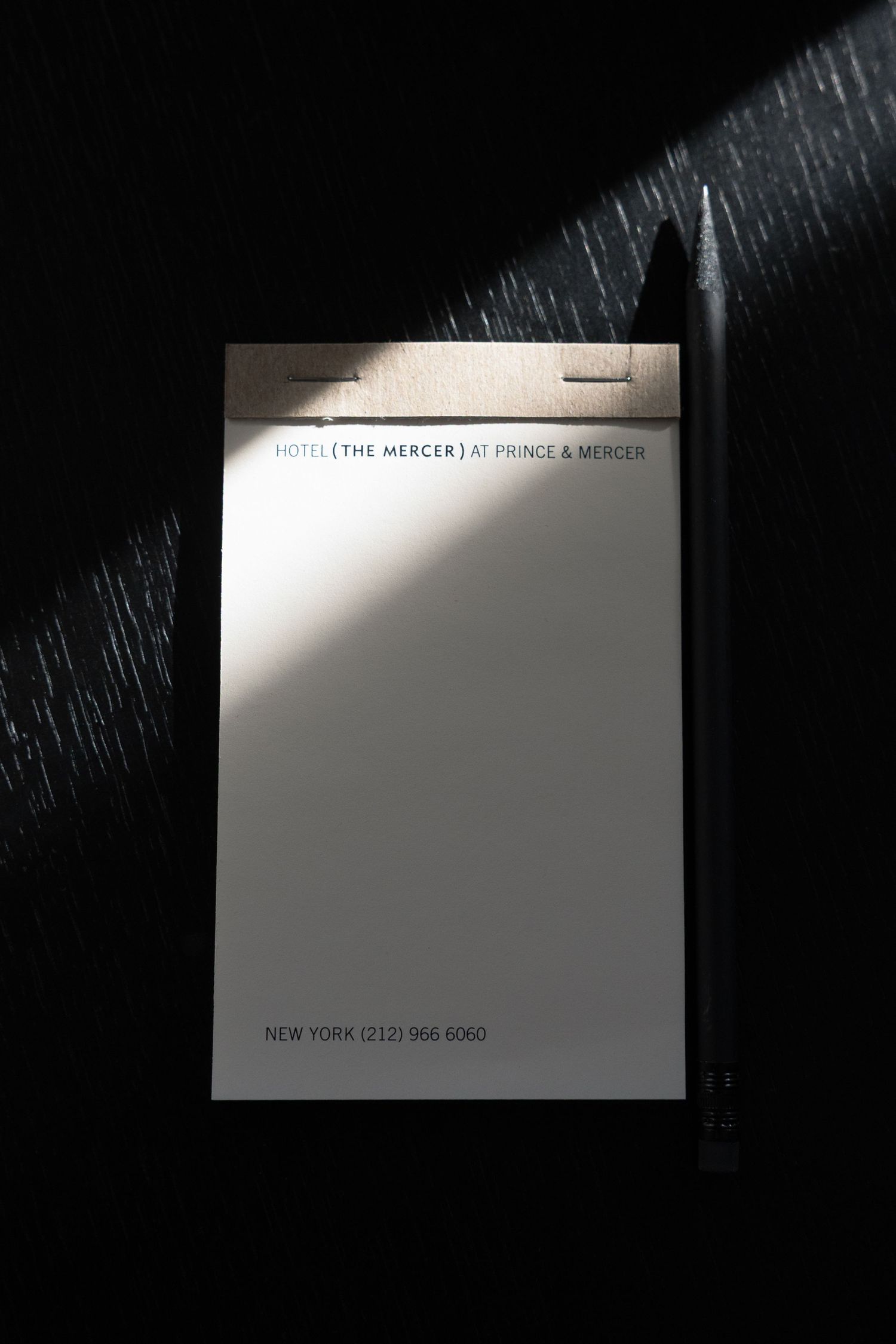Business card on dark textured surface with contact information partially visible.