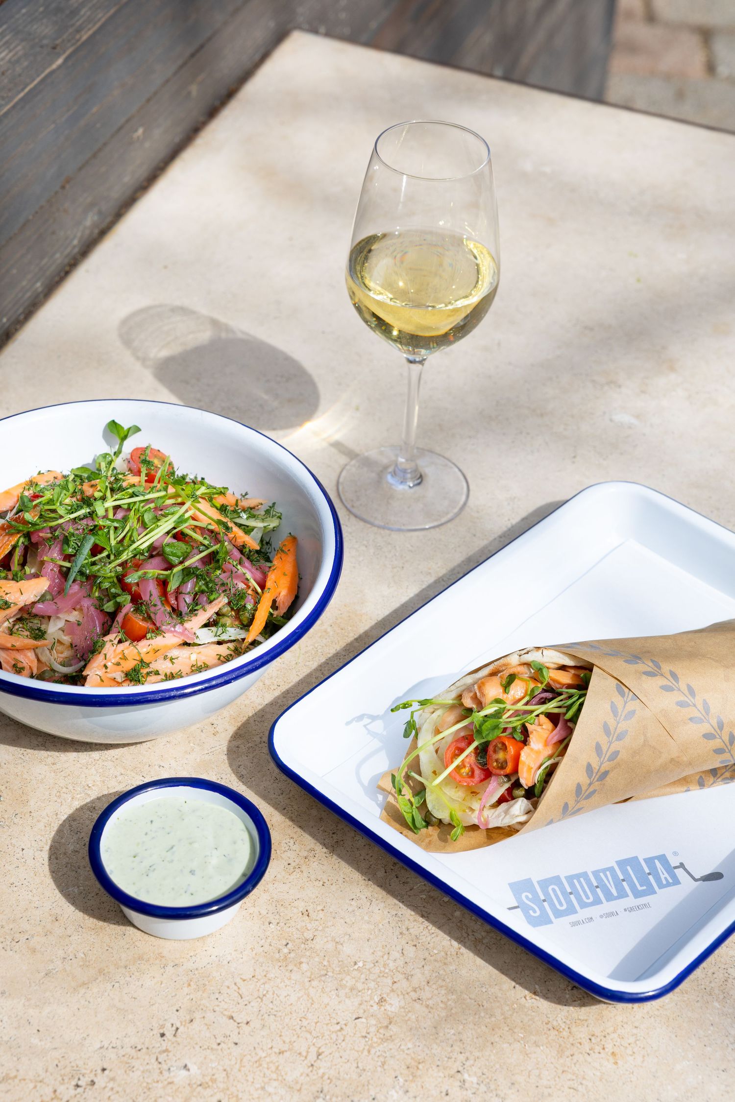 Artfully plated meals on white and blue rimmed dishes with wine pairings on stone surface.