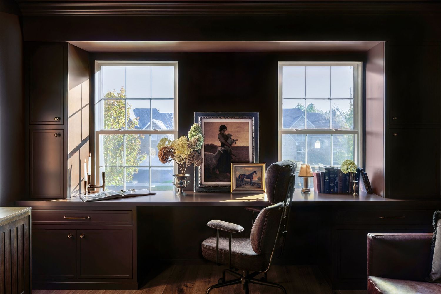 A dark wood-paneled interior room with windows letting in natural light and showing exterior views.