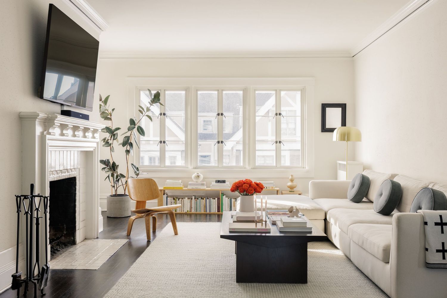 Elegant living room with white walls, fireplace, large sectional sofa, black coffee table, and bright windows.