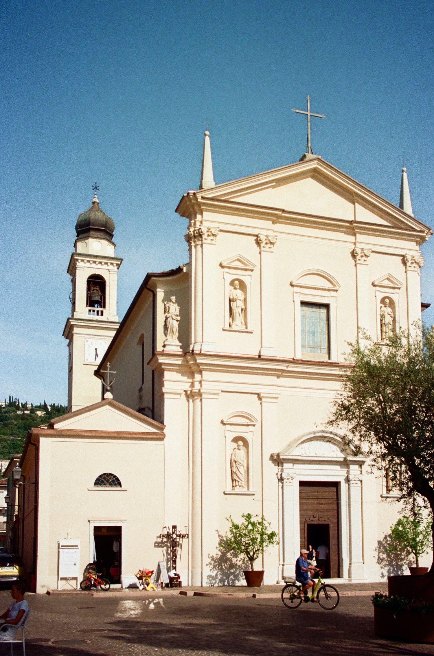 Traditional Italian church with bell tower and classical architecture against blue sky.