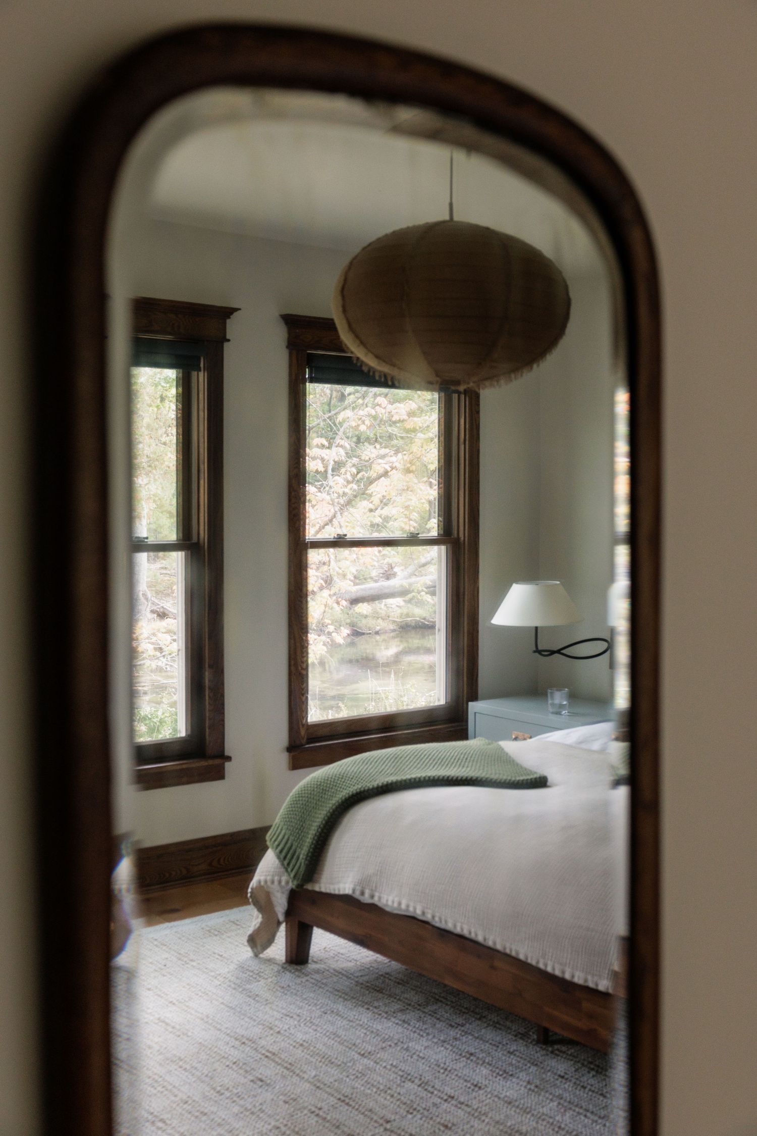 Serene bedroom interior viewed through an arched doorway with natural light and minimal decor.