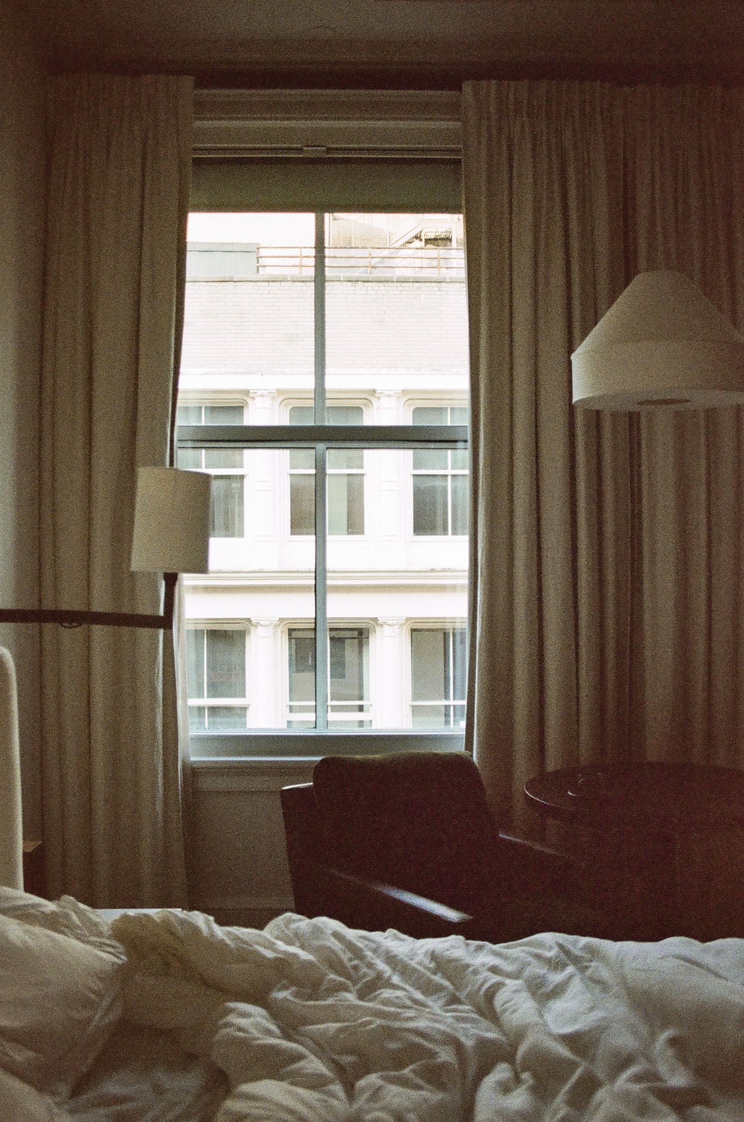 Unmade bed with rumpled white linens in a bright, modern hotel room.