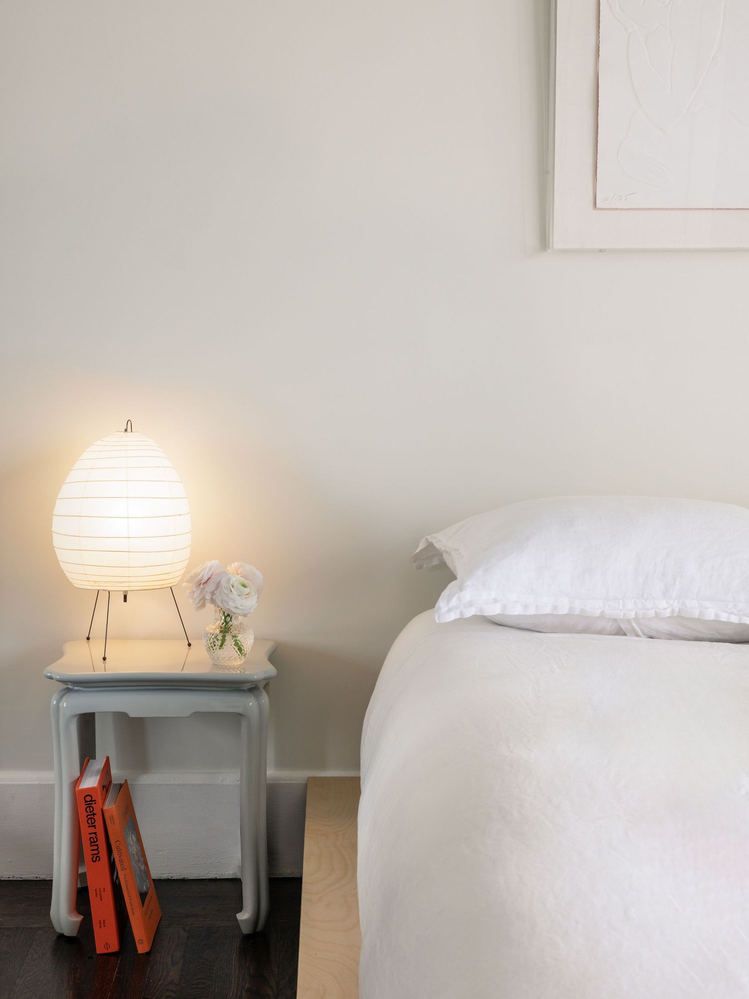 Serene bedroom setting with white bedding, paper lantern light and pale blue walls.