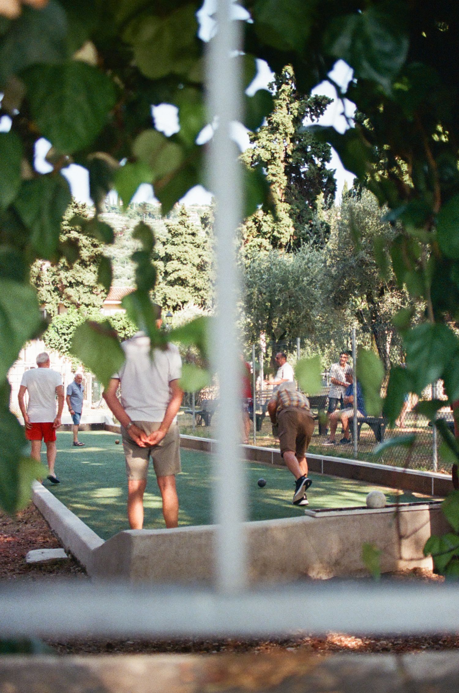 People playing mini golf on an outdoor course surrounded by trees and greenery.
