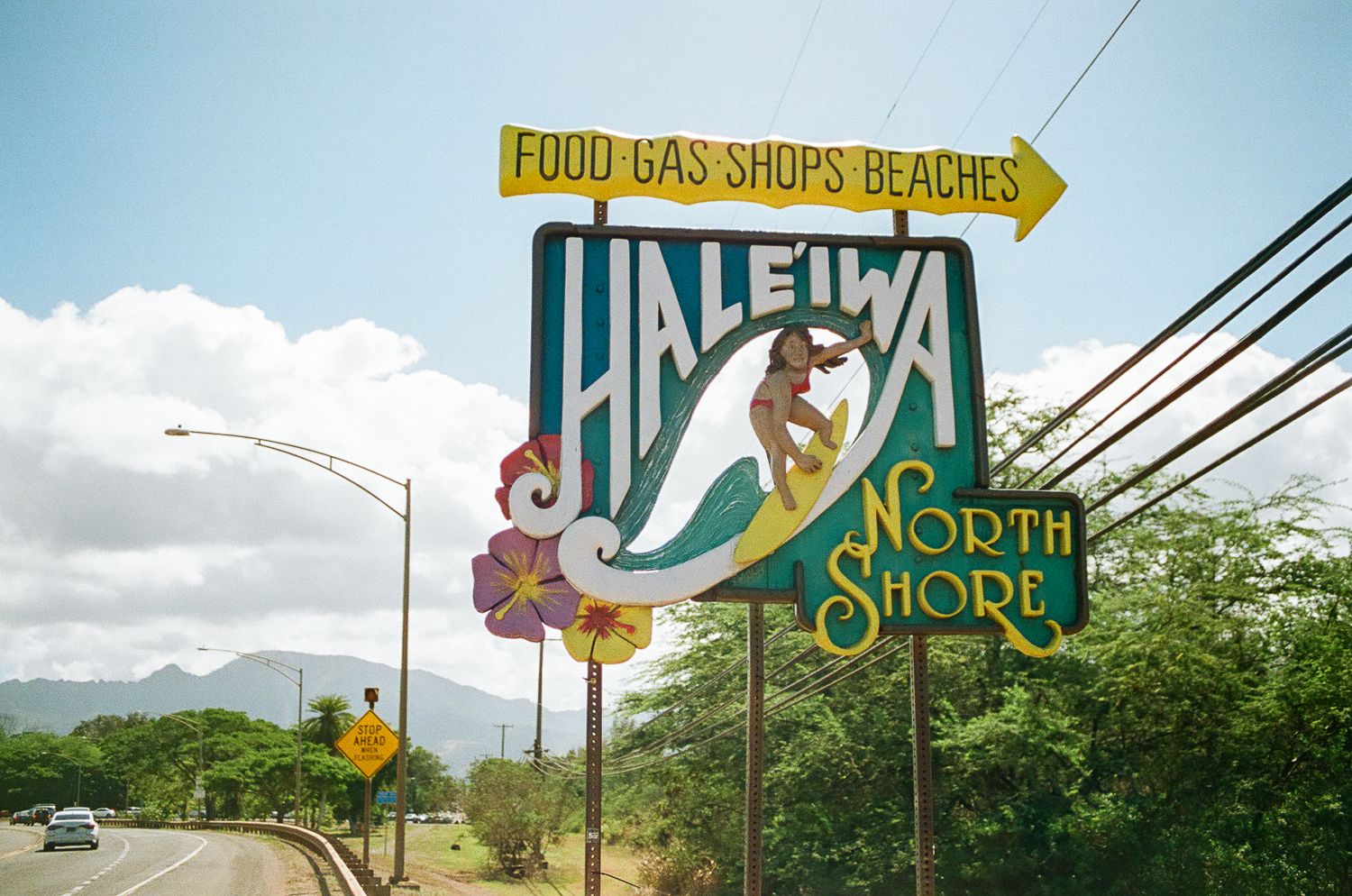 Roadside signs pointing to food, gas, and shops along the North Shore of Hawaii.