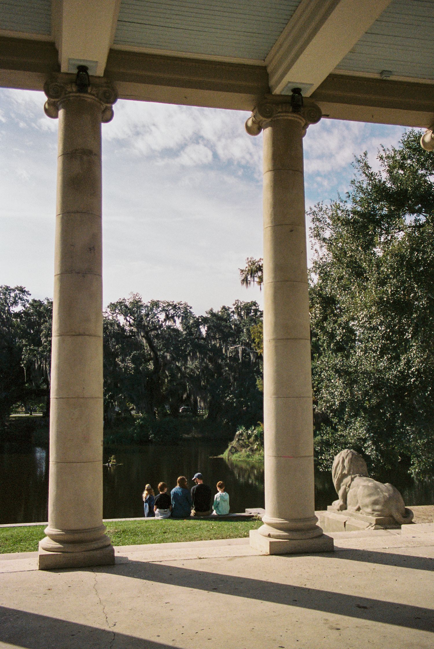 Classical columned portico overlooking a garden with stone lion statue.