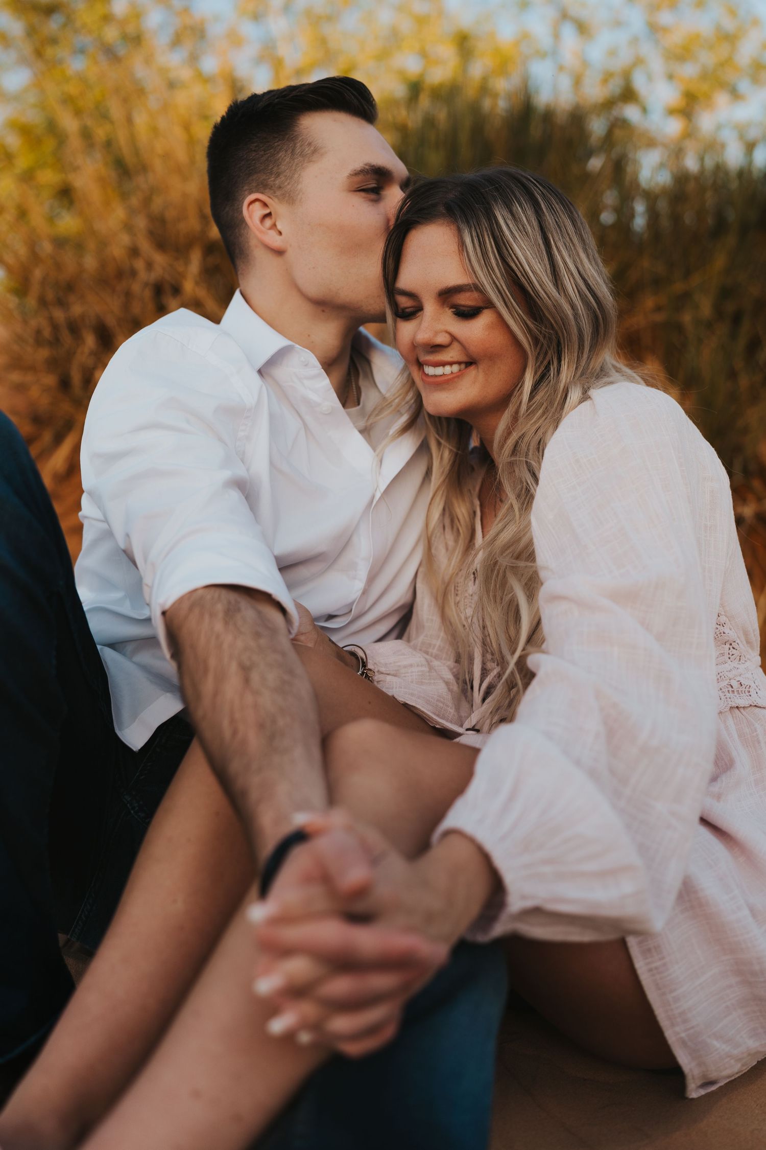 Intimate autumn engagement photos with couple in white clothing against fall foliage.