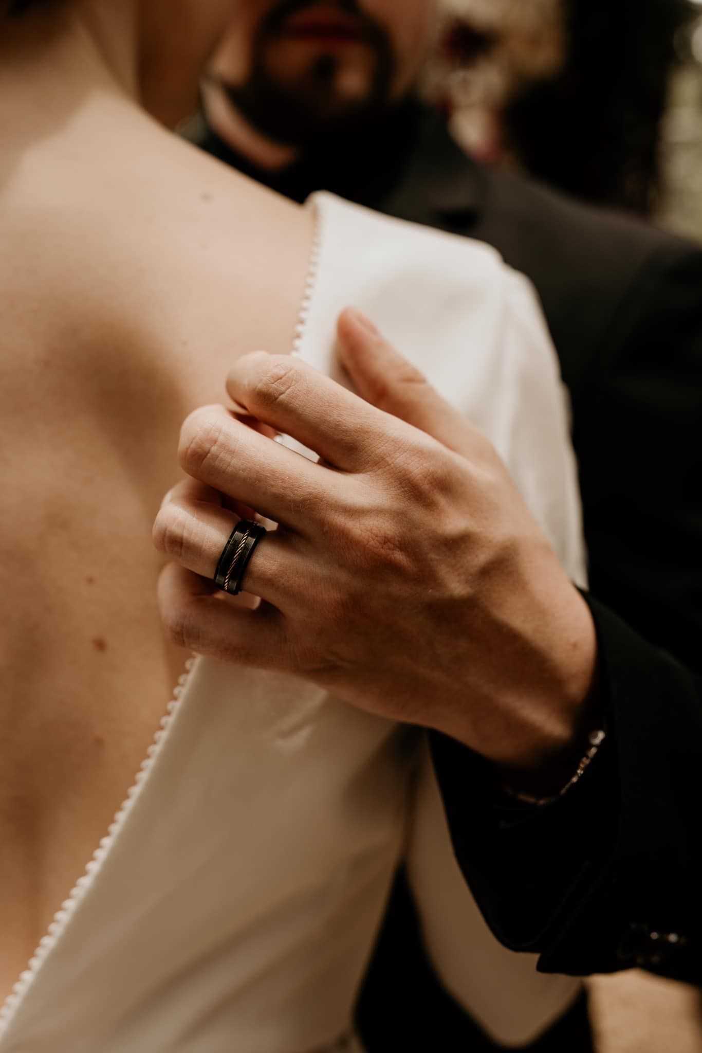 Close-up detail shot of hands holding a white dress with pearl buttons.