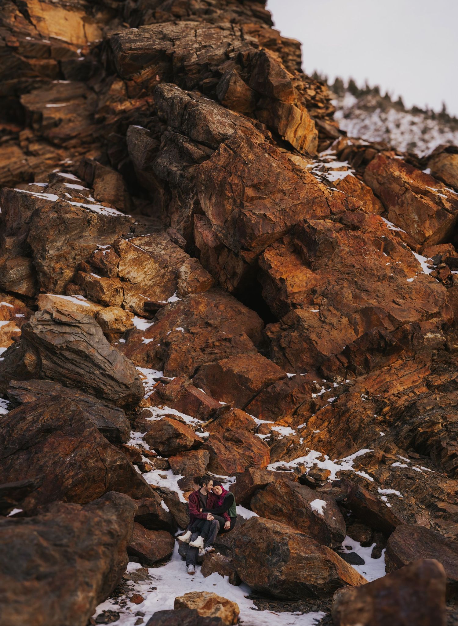 Rocky mountainside with patches of snow and rustic orange-colored stone formations.