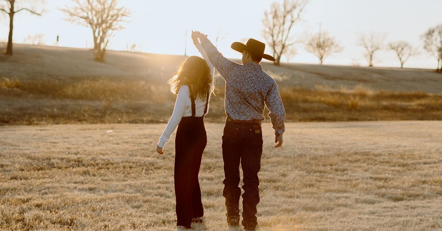Silhouetted couple walking together in golden sunset field.