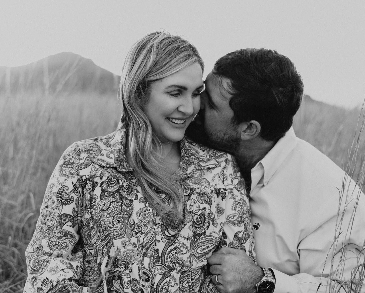 Black and white portrait of couple sharing intimate moments in natural setting.