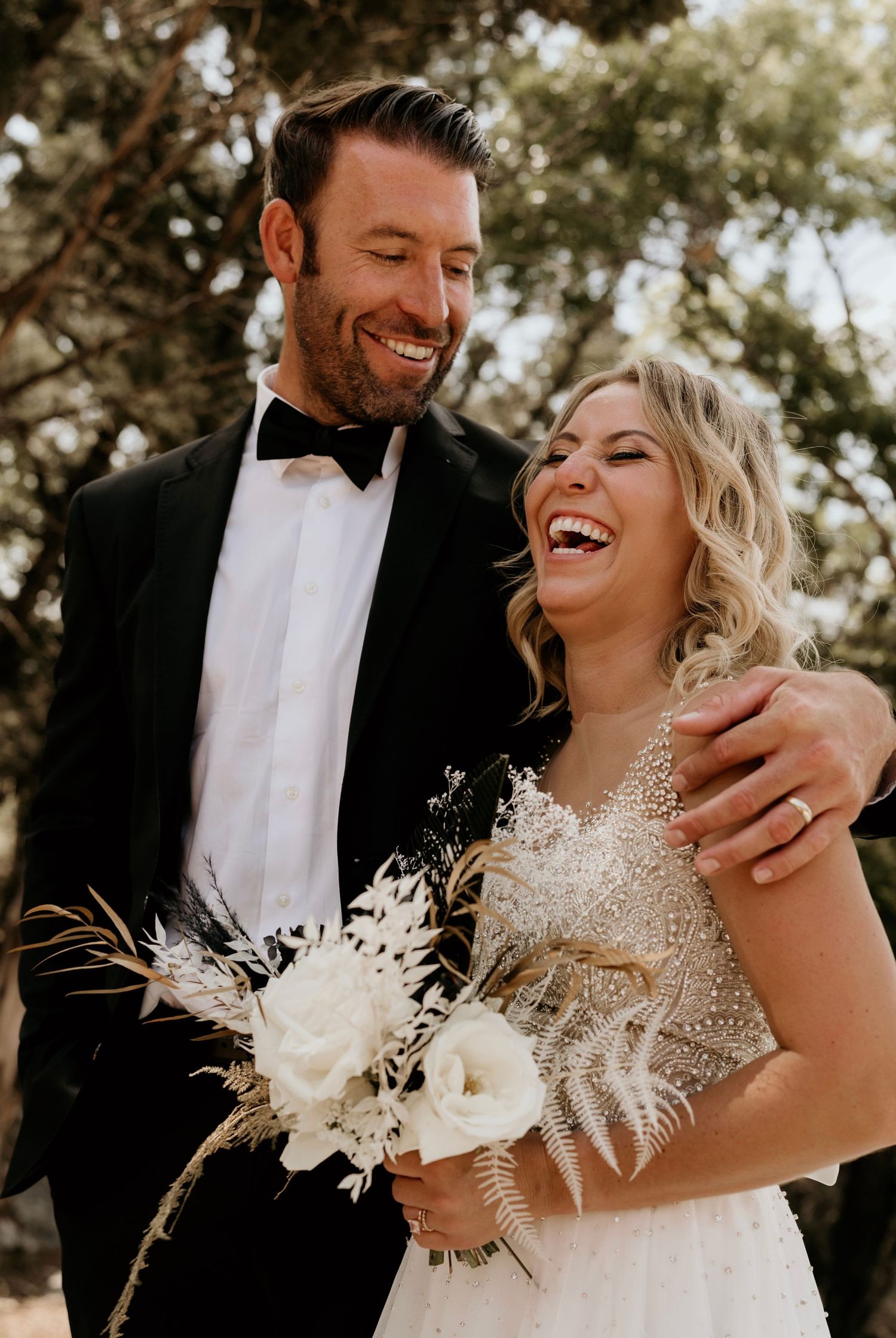 A joyful wedding moment with white dried flower bouquet and formal attire.