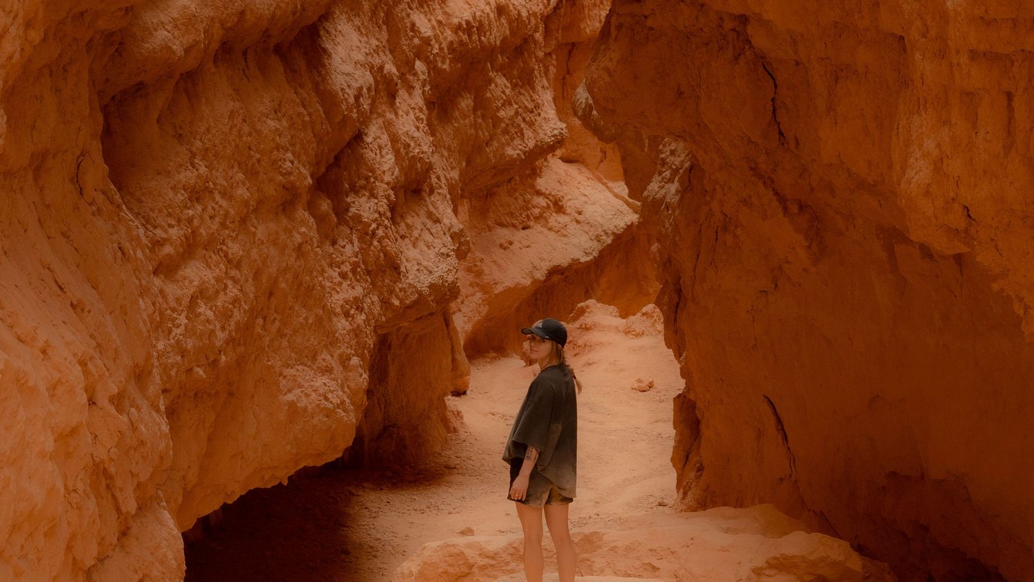 Silhouette walking through red rock canyon tunnel.