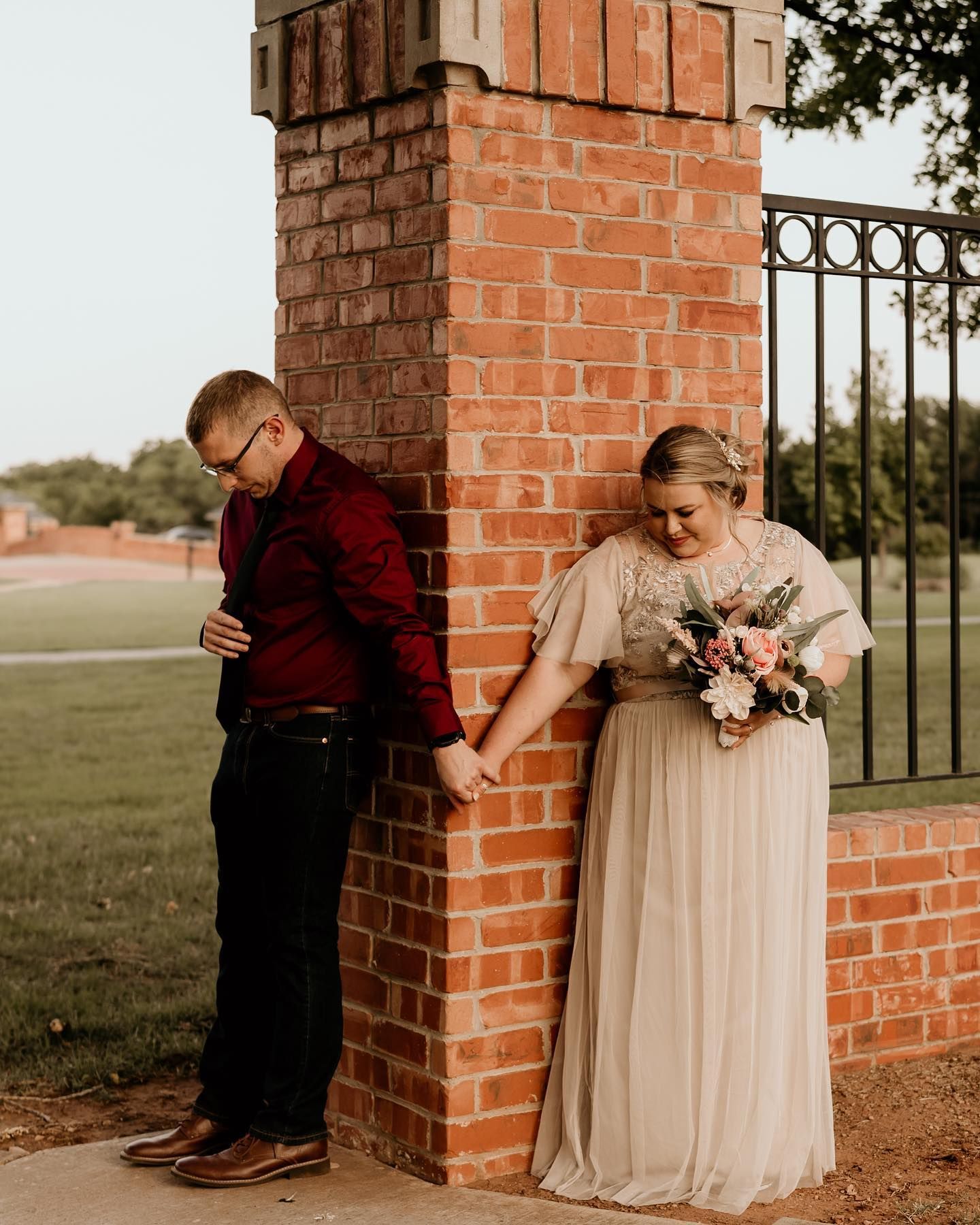 Couple shares tender moment against brick wall during romantic outdoor photo session.