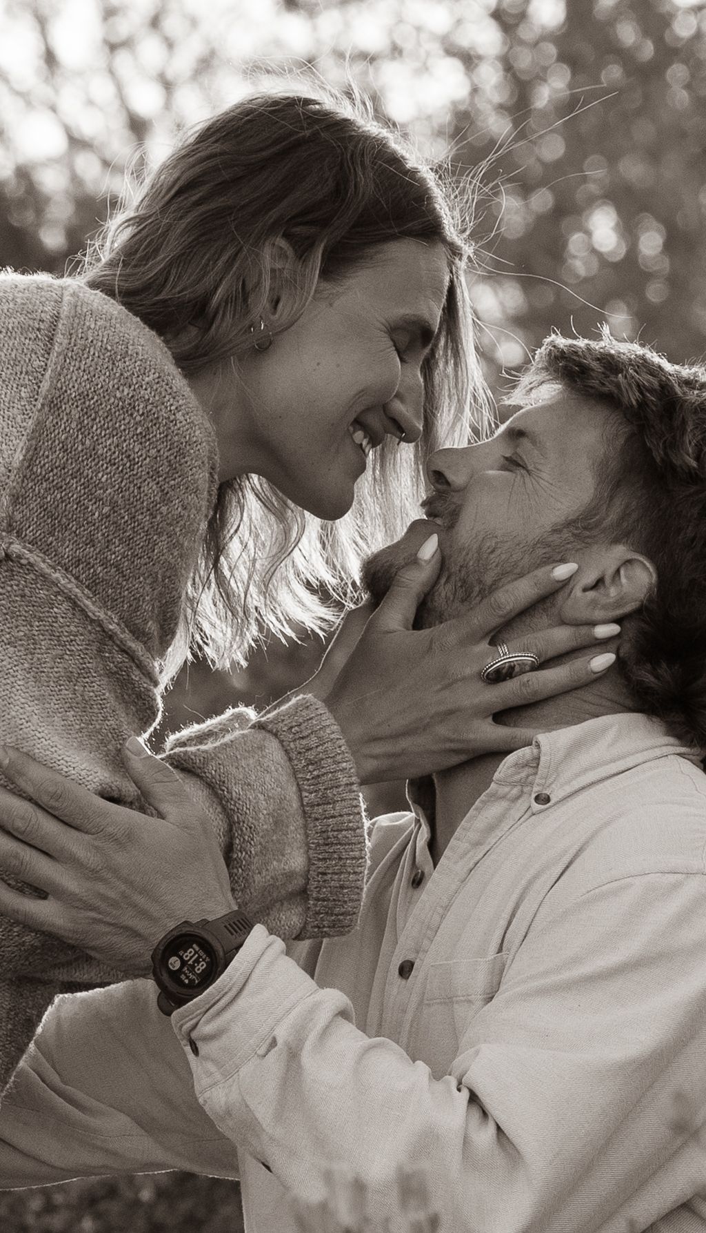 Romantic couple sharing a tender moment, smiling and about to kiss in black and white portrait.