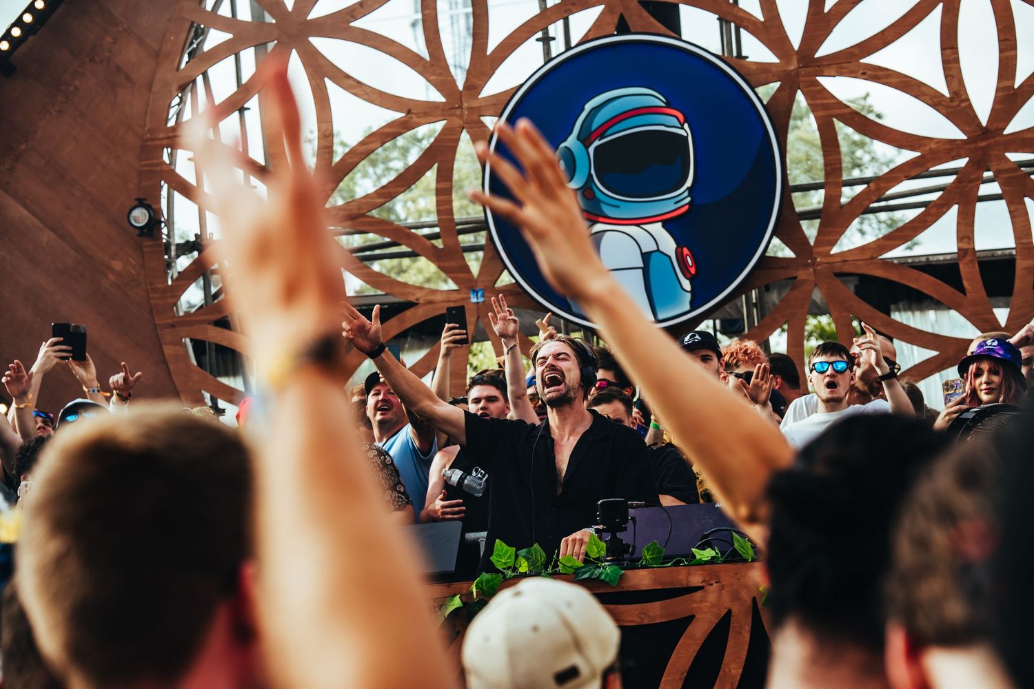 Crowd cheering at festival stage with DJ booth