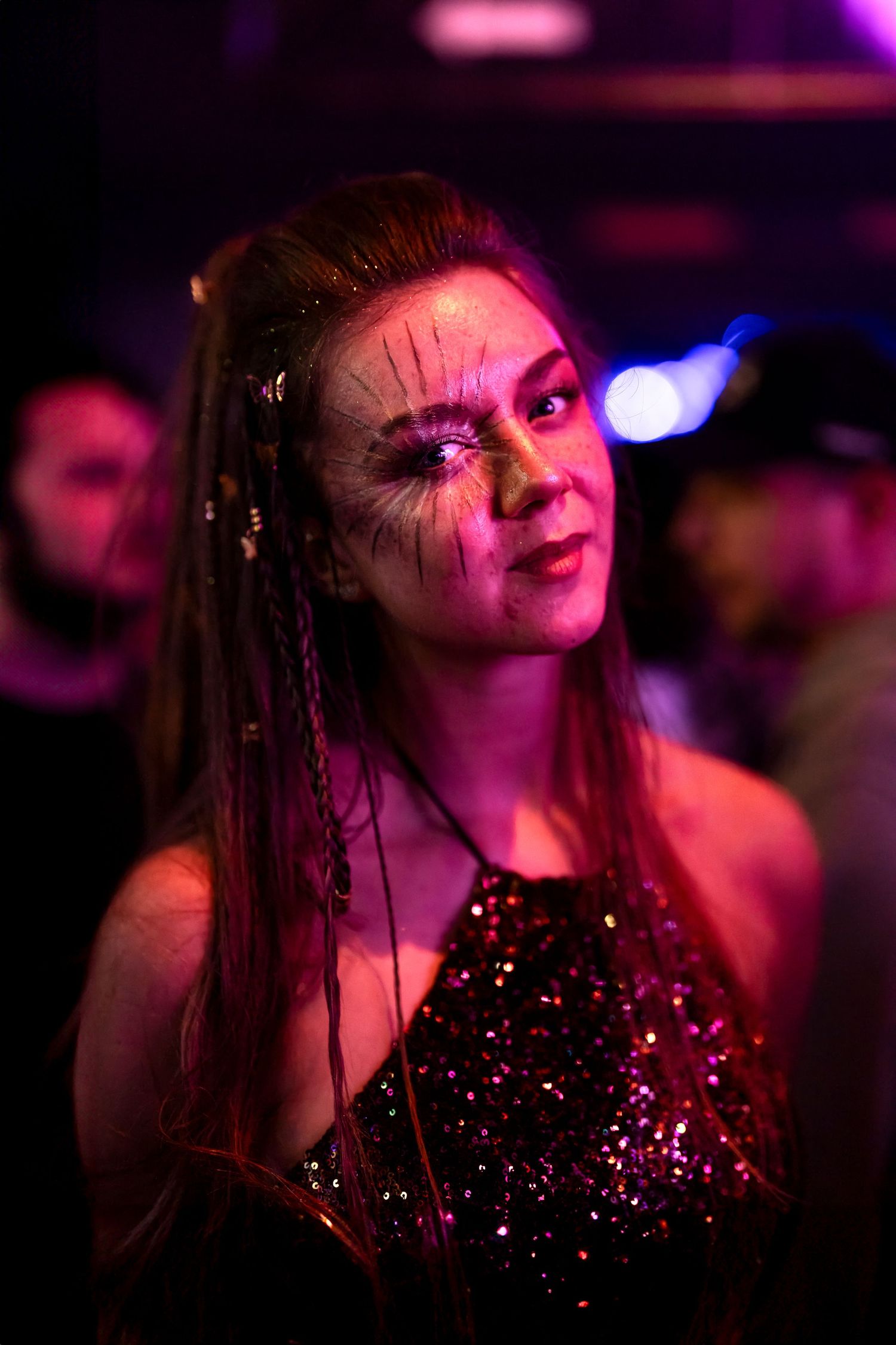 Festival portrait of woman with face paint in colorful stage light