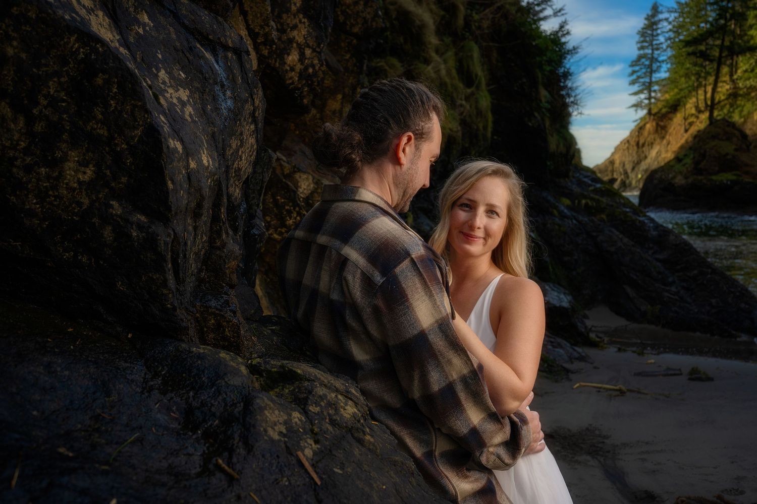 Romantic couple photoshoot at a scenic rocky beach during golden hour.