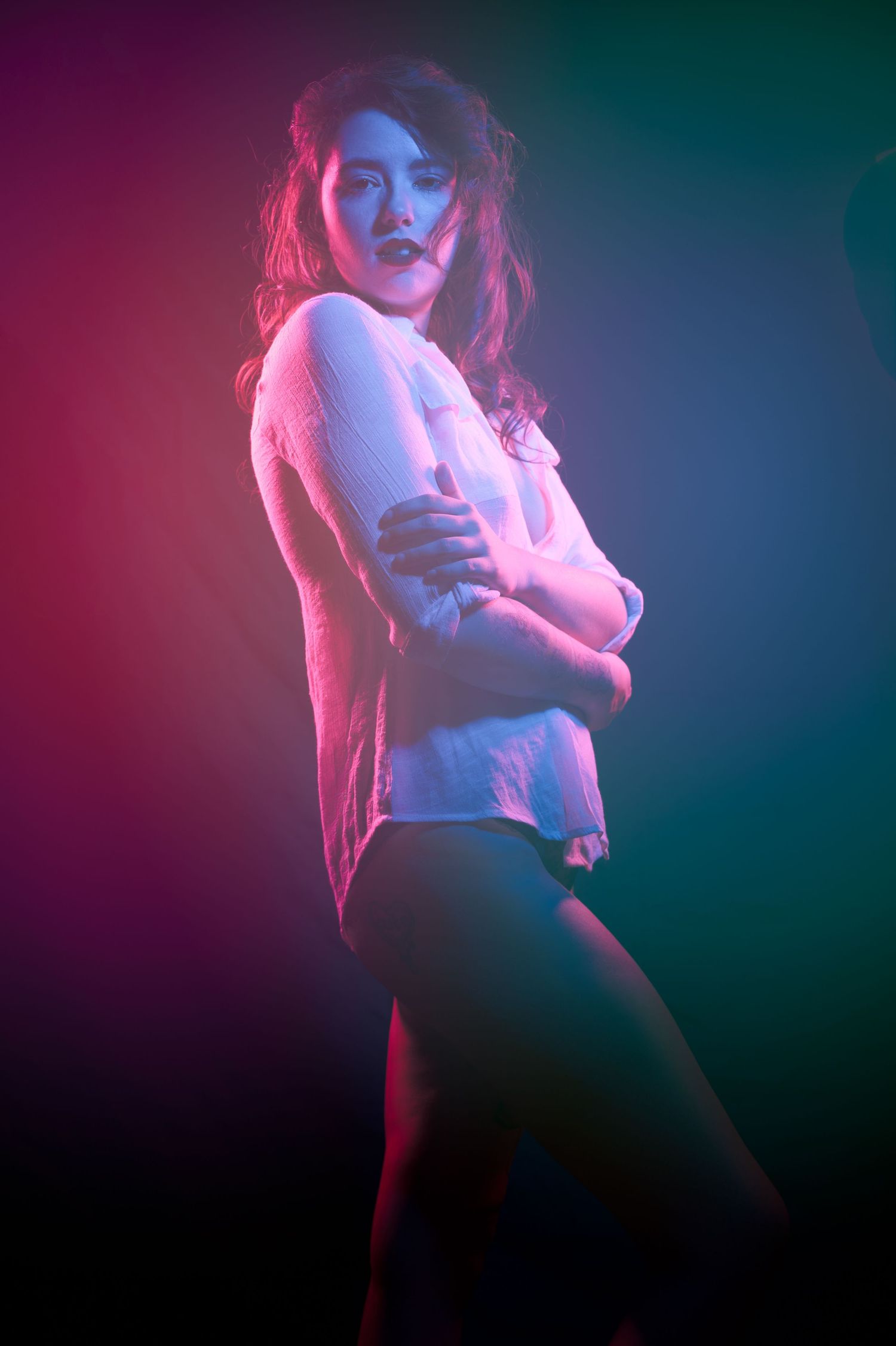 Dramatic portrait with neon pink and blue lighting effects against dark background.