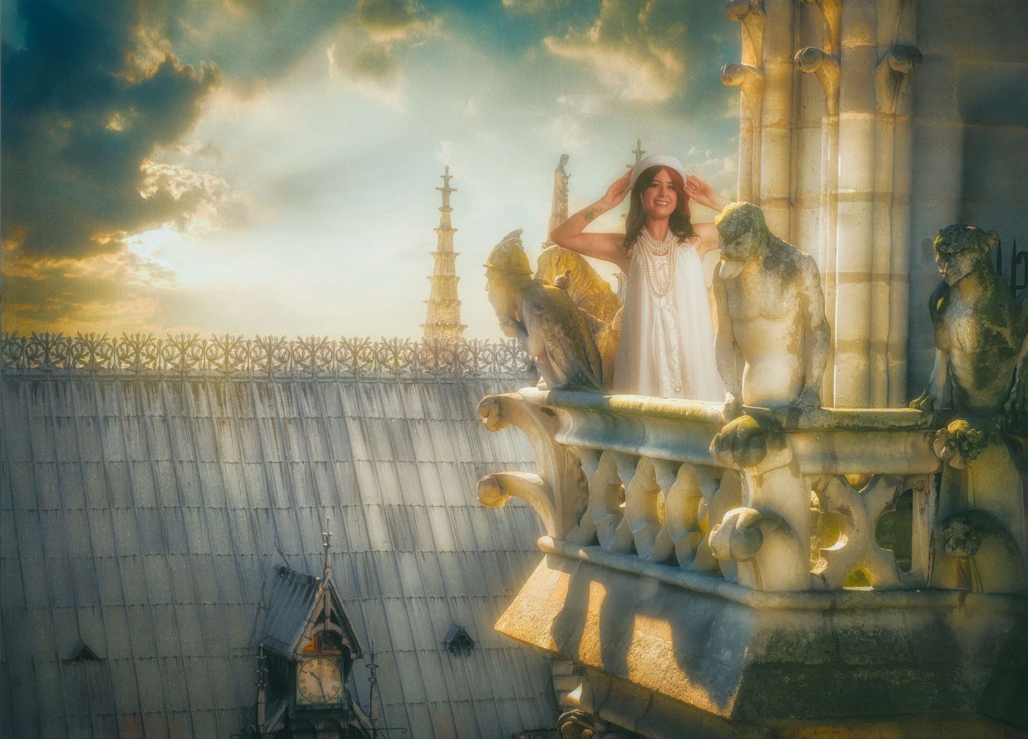 A woman in white dress stands on Gothic cathedral balcony with gargoyles at golden sunset.