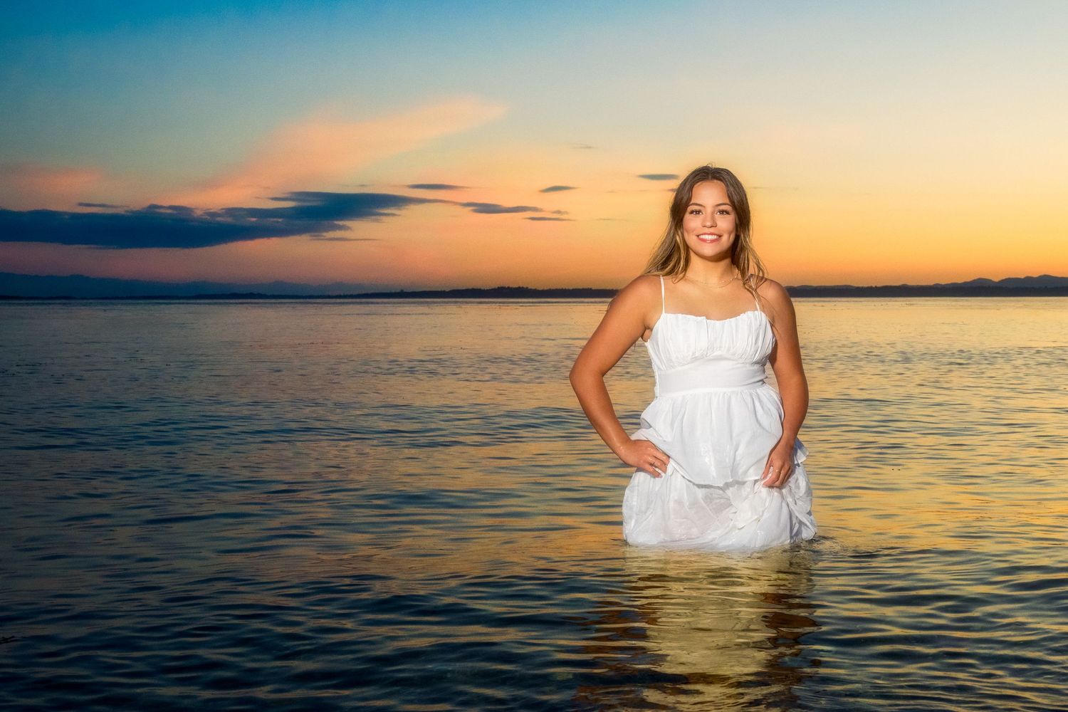 Stunning ocean sunset photos with a figure in a white dress wading in calm waters.