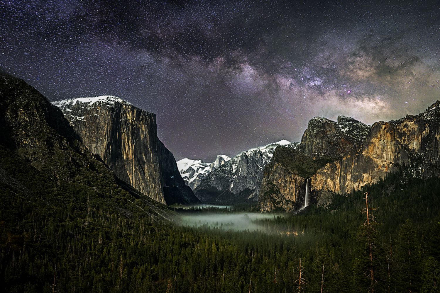 Moonlit valley of Yosemite National Park with dramatic mountain peaks under night sky.