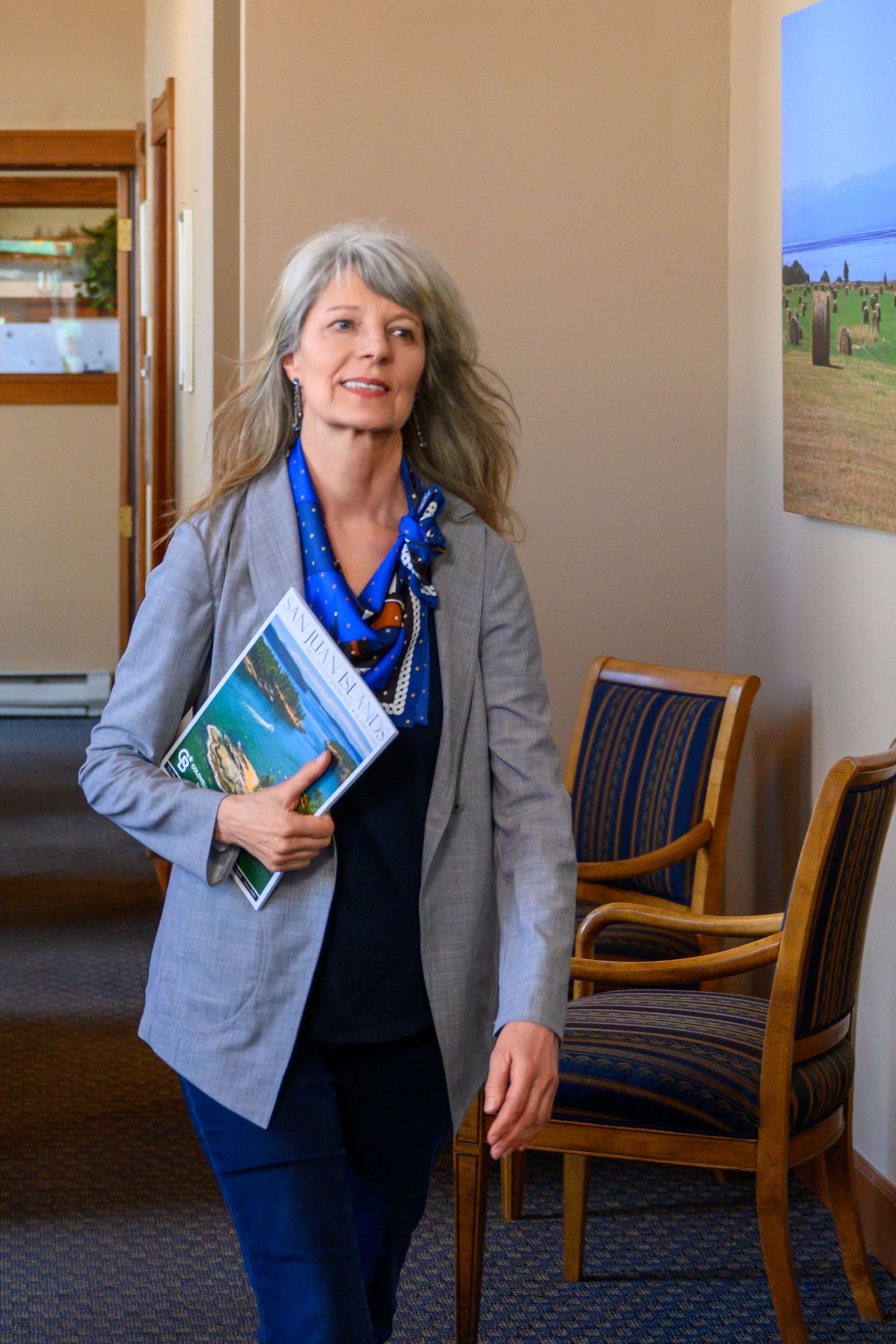 A series of photos showing someone in a gray blazer and blue scarf holding books in an office setting.