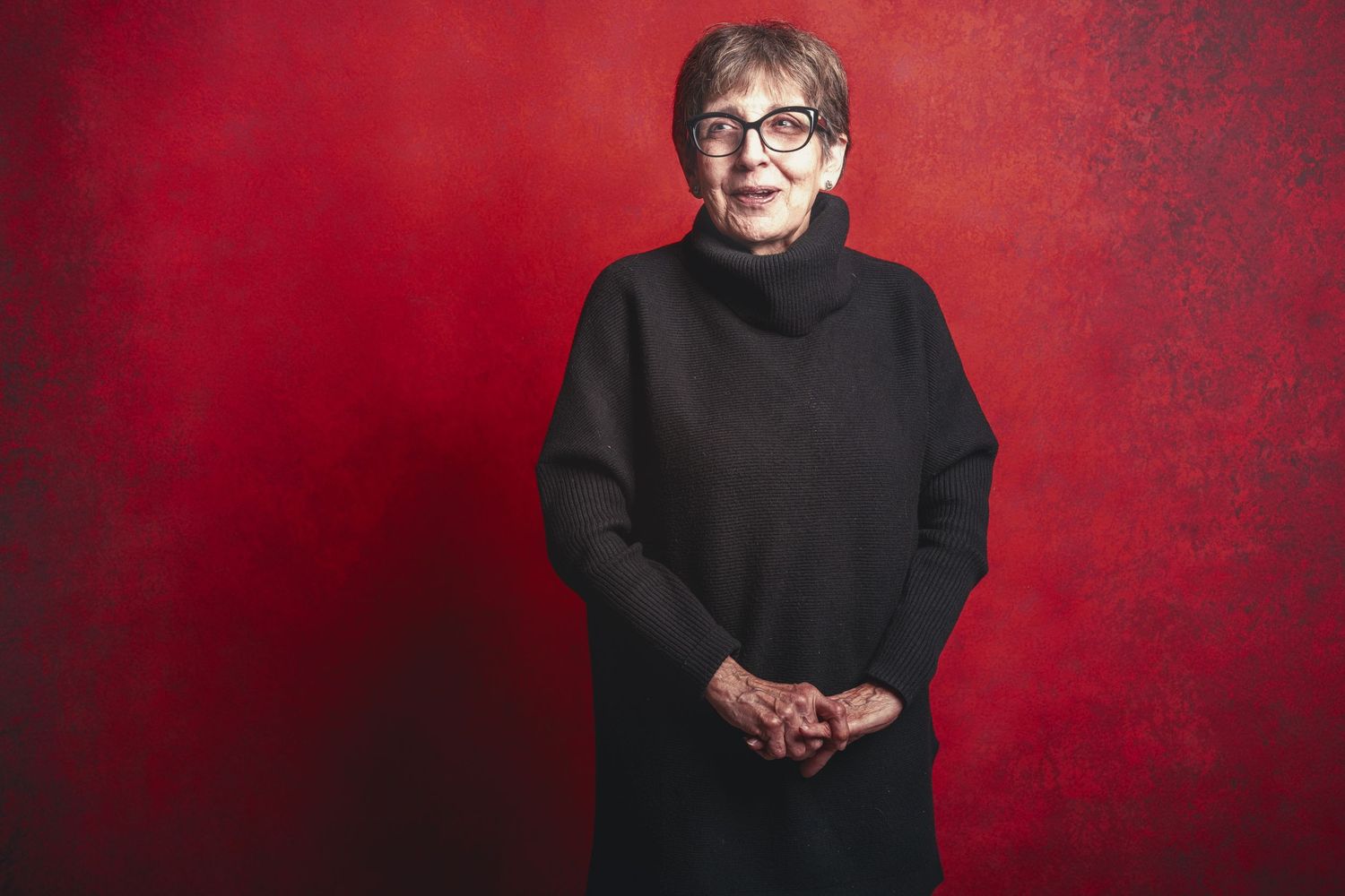 Portrait series against red backdrop showing various poses in black attire.