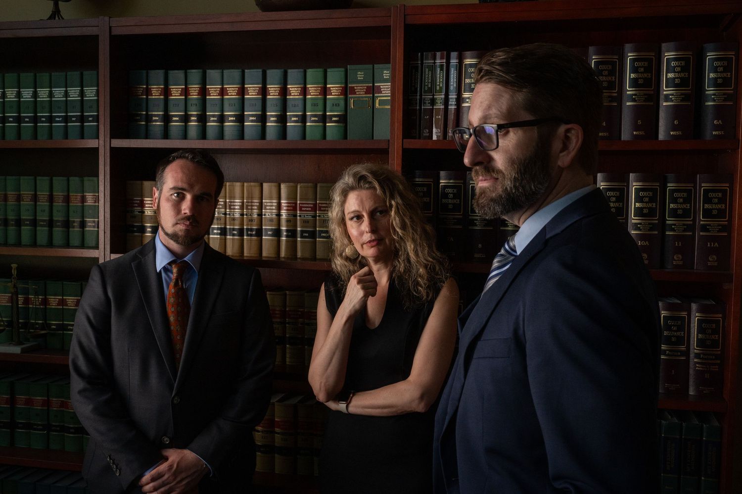 Professional business portraits in a law library with dark wood shelving and legal books.