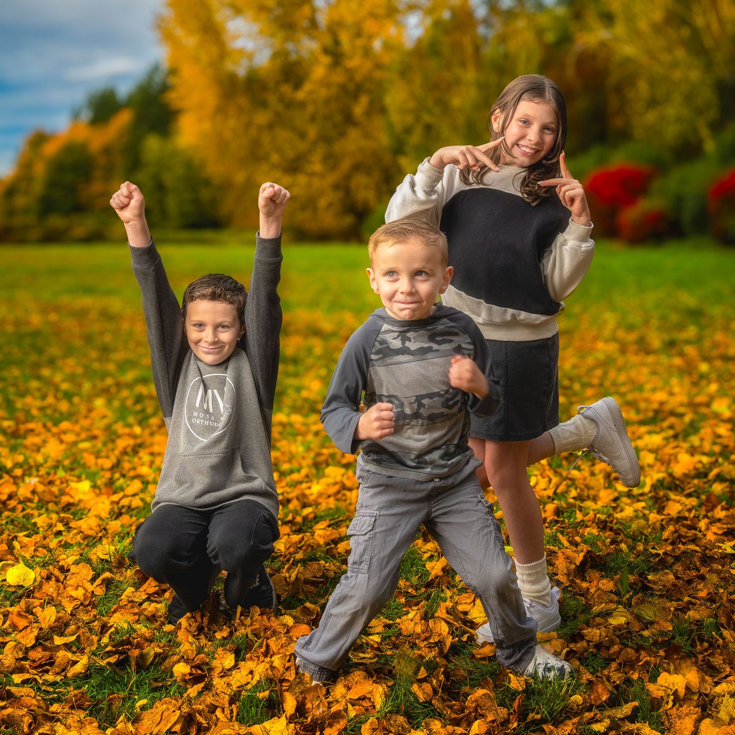 Children playing and jumping in autumn leaves on a sunny day.
