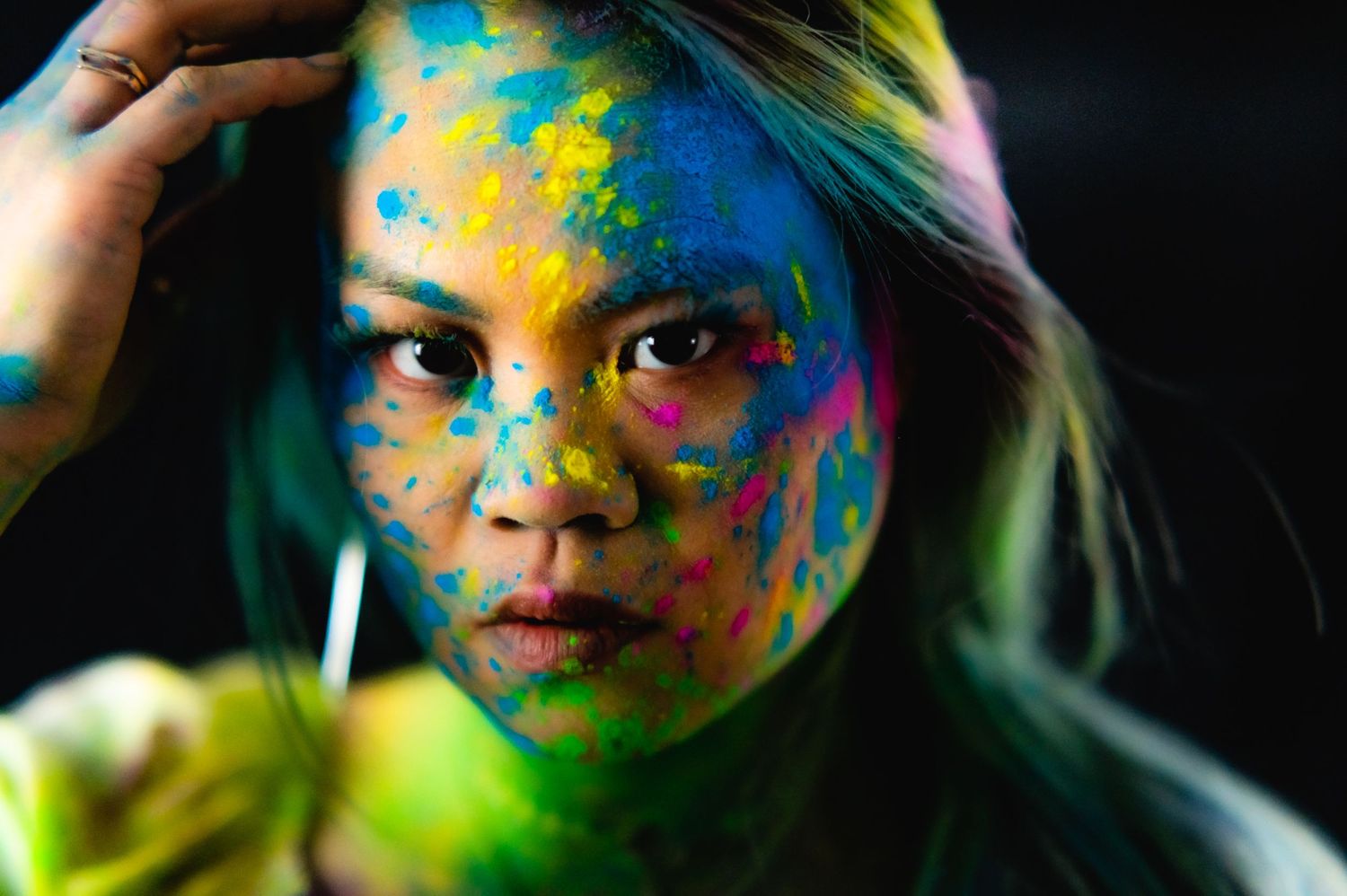 Creative beauty portraits with colorful powder paint makeup against dark background.